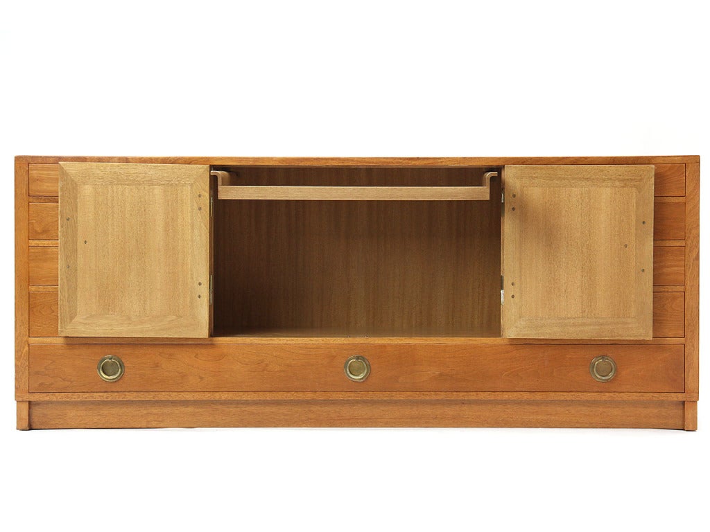 A walnut server with central compartment having a removable glass-bottom serving tray & one adjustable shelf, flanked by two banks of four drawers over one long drawer all with brass hardware, on a plinth base.