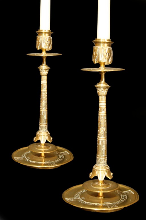 #K544 - Charming pair of Egyptian revival candlesticks incorporating various exotic Egyptian motifs including pharaohs head and hieroglyphics. Beginning with Napoleon's Egyptian campaign of 1799, Egyptian motifs became fashionable in the decorative