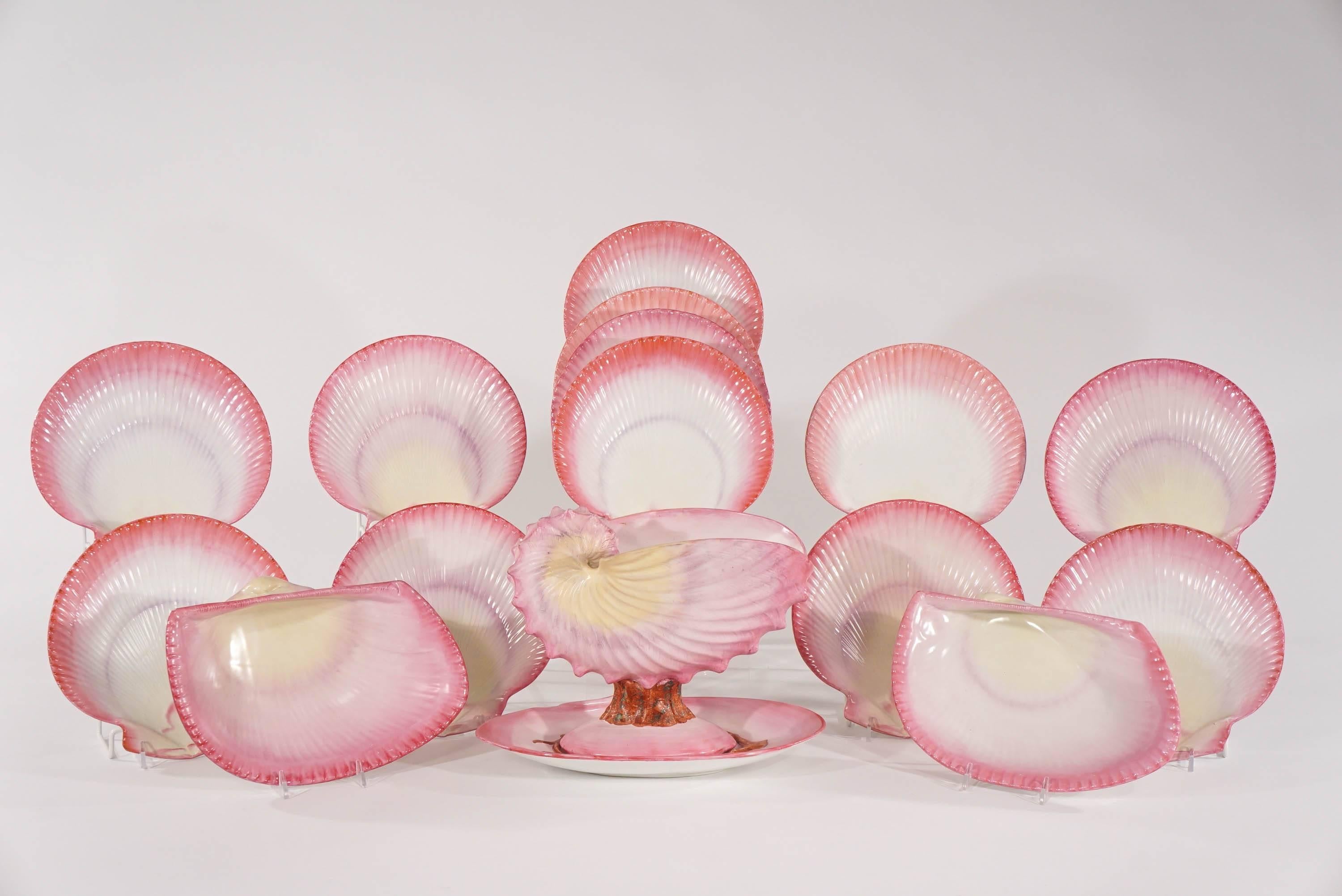 This 19th century Wedgwood dessert service consists of a footed centerpiece and stand, 12 scallop shaped dessert plates and two large clam shell plates with a shaded pink glaze that varies on each piece. The molded plates are realistically shaped as