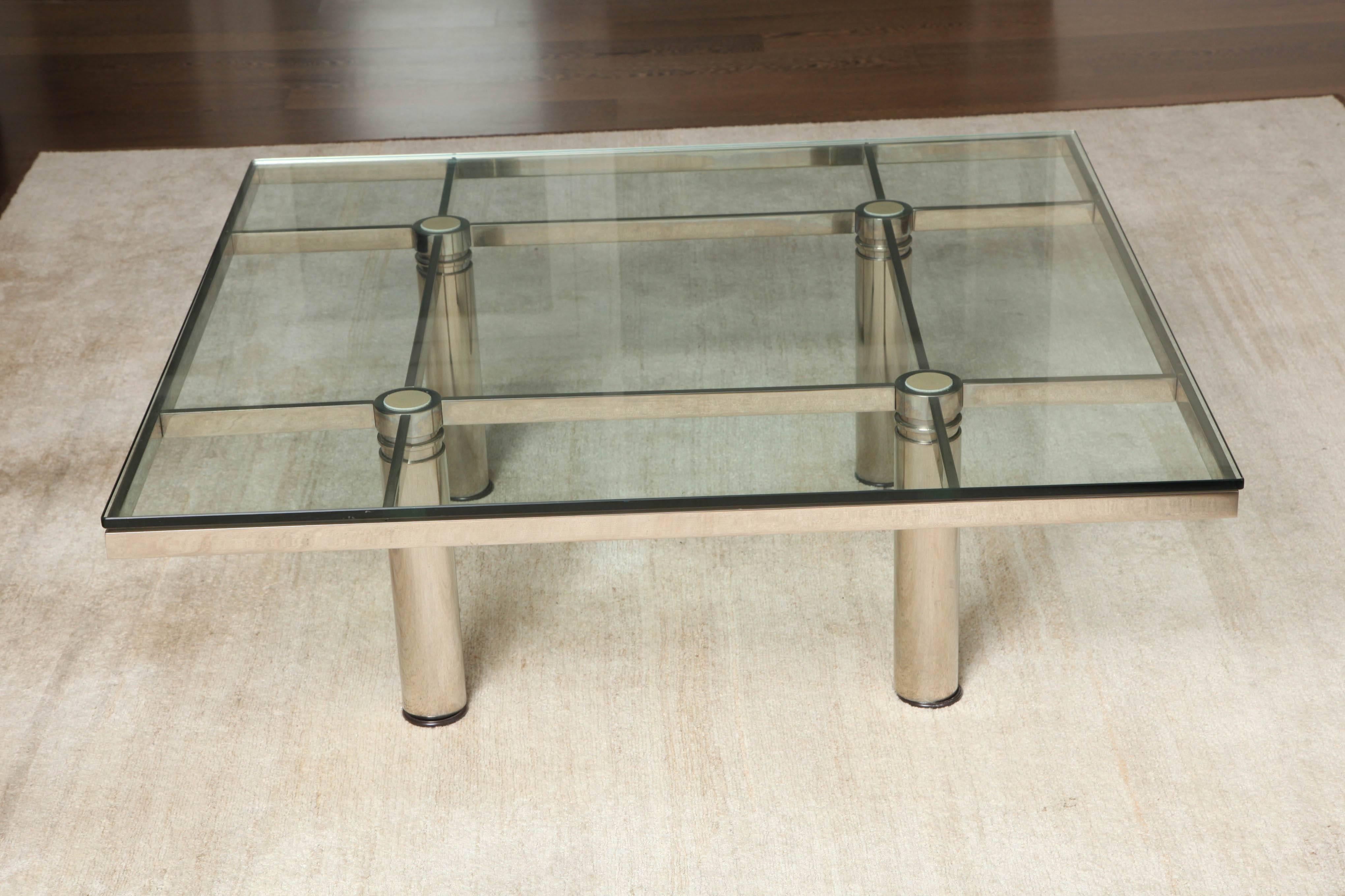 Chrome-plated steel table inset with a glass top supported on four round legs topped with leather inserts.