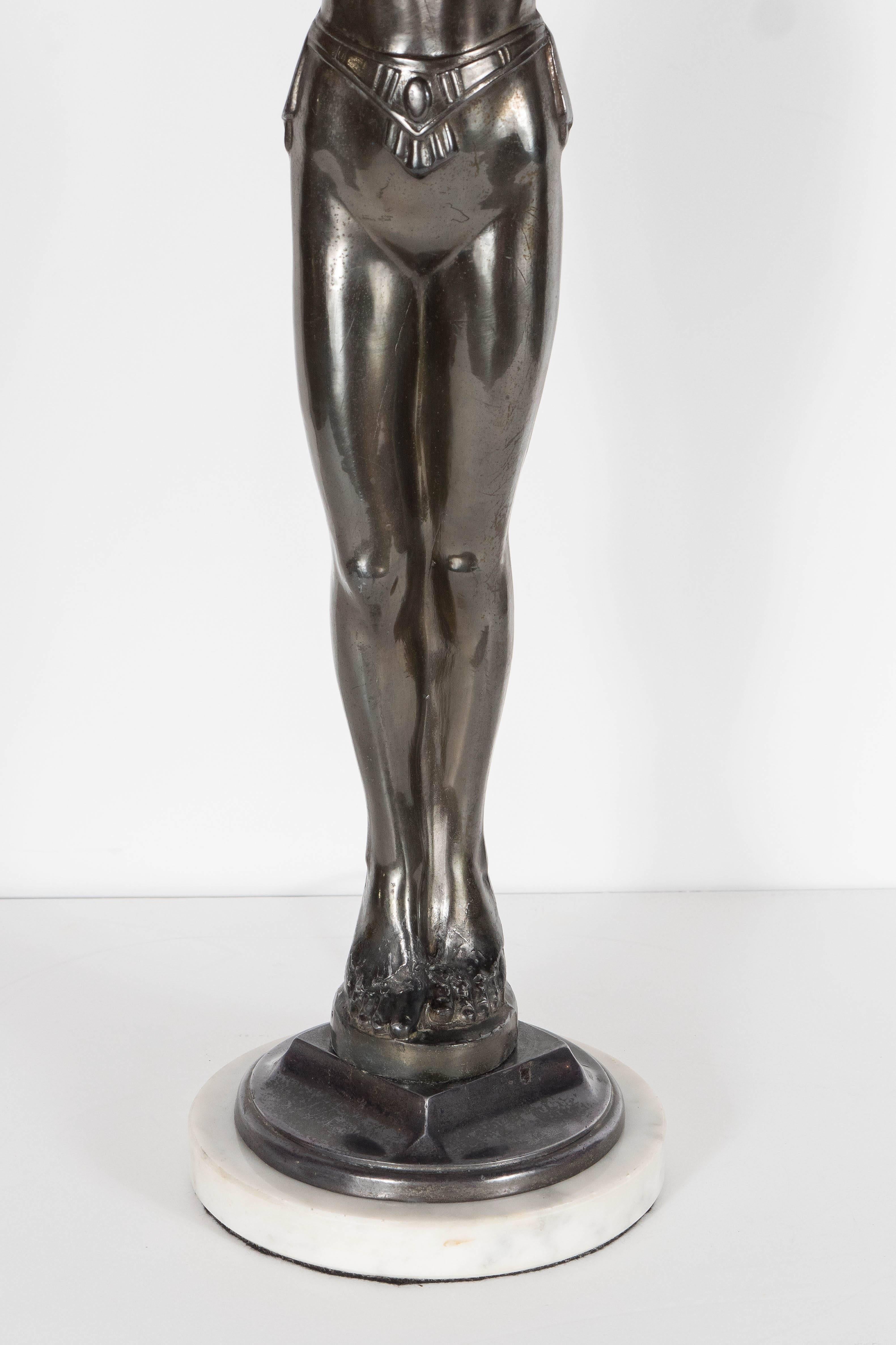 This elegant Art Deco patinated bronze uplight by Everlite features a figurative depiction of a 1920's flapper girl, her body is stretched out to form the stem of the lamp as she reaches up to support a white glass rounded lampshade. She is
