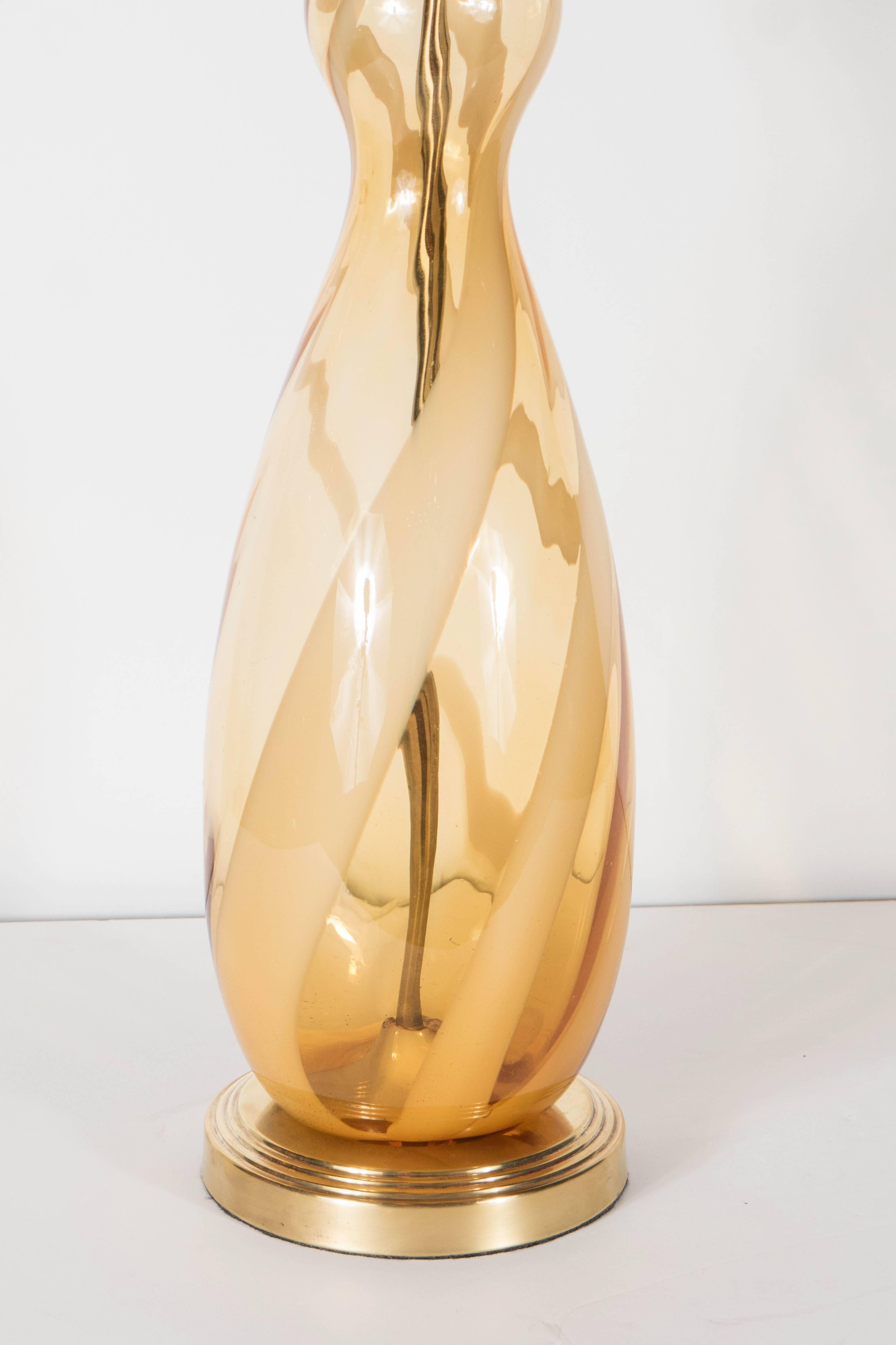 Mid-Century Modernist table lamp comprised of hand-blown Murano glass in a balustrade form shape. This lamp is featured in a dark, smoked Amber. The stripes that follow the lamps curvature alternate in clear and opaque smoked Amber.  It sits atop a