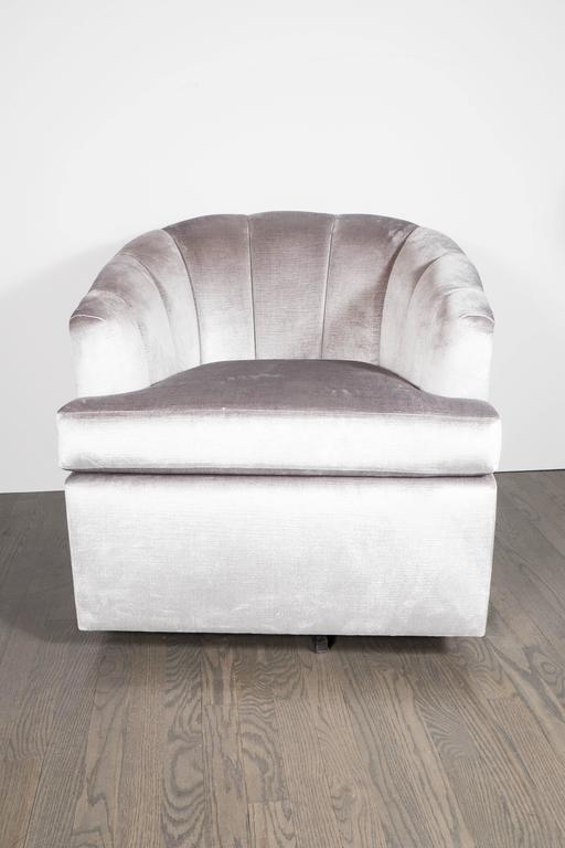 Sophisticated pair of Mid-Century Modernist channel back swivel chairs by Milo Baughman in a chic platinum velvet upholstery. This pair of swivel chairs by Milo Baughman feature a fully upholstered design with a curved channel back. These gorgeous