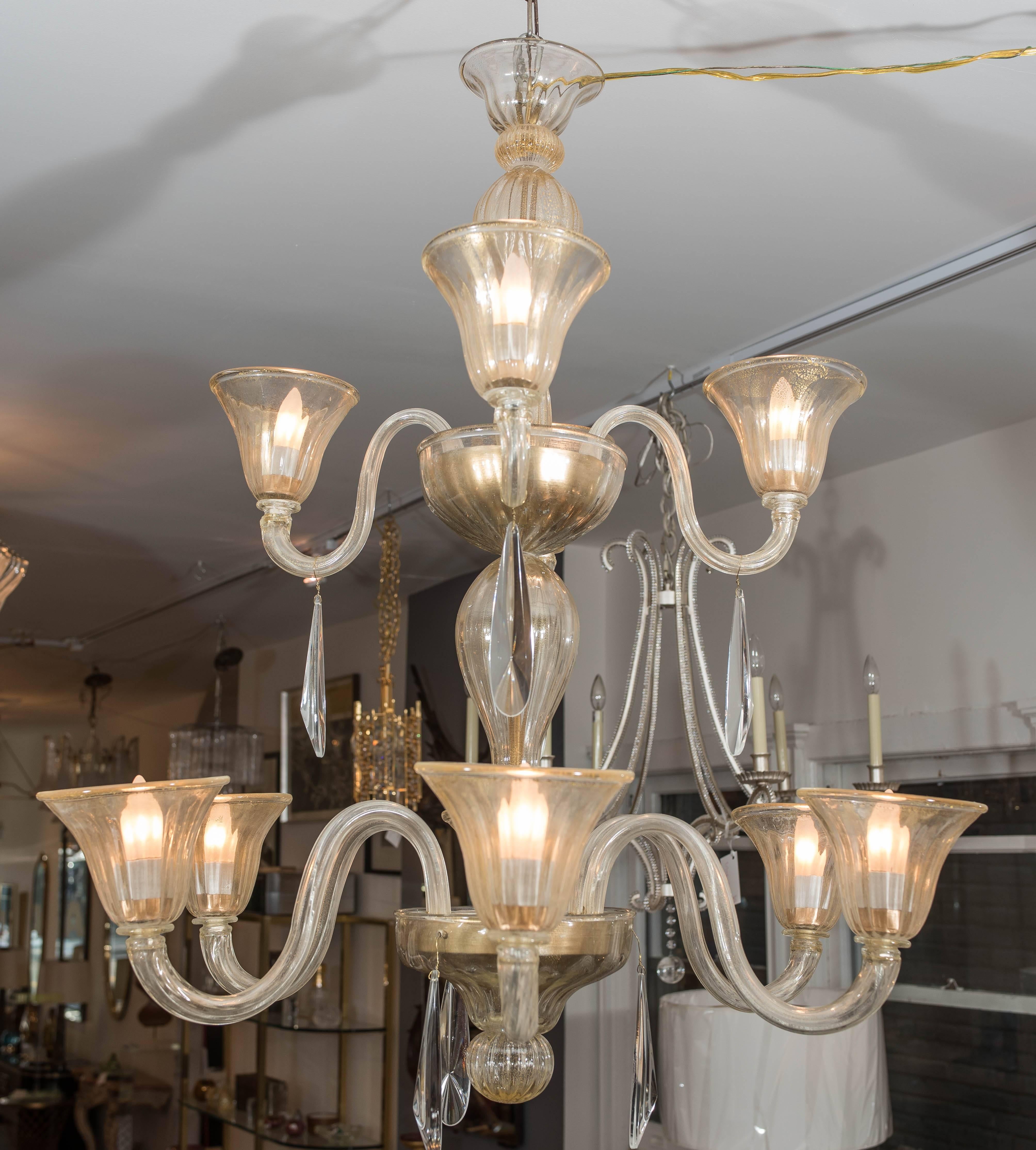 This large and elegant chandelier is beautifully made with gold infused glass and accented with clear crystal drops. It is wired for North America and can be easily disassembled for shipping.