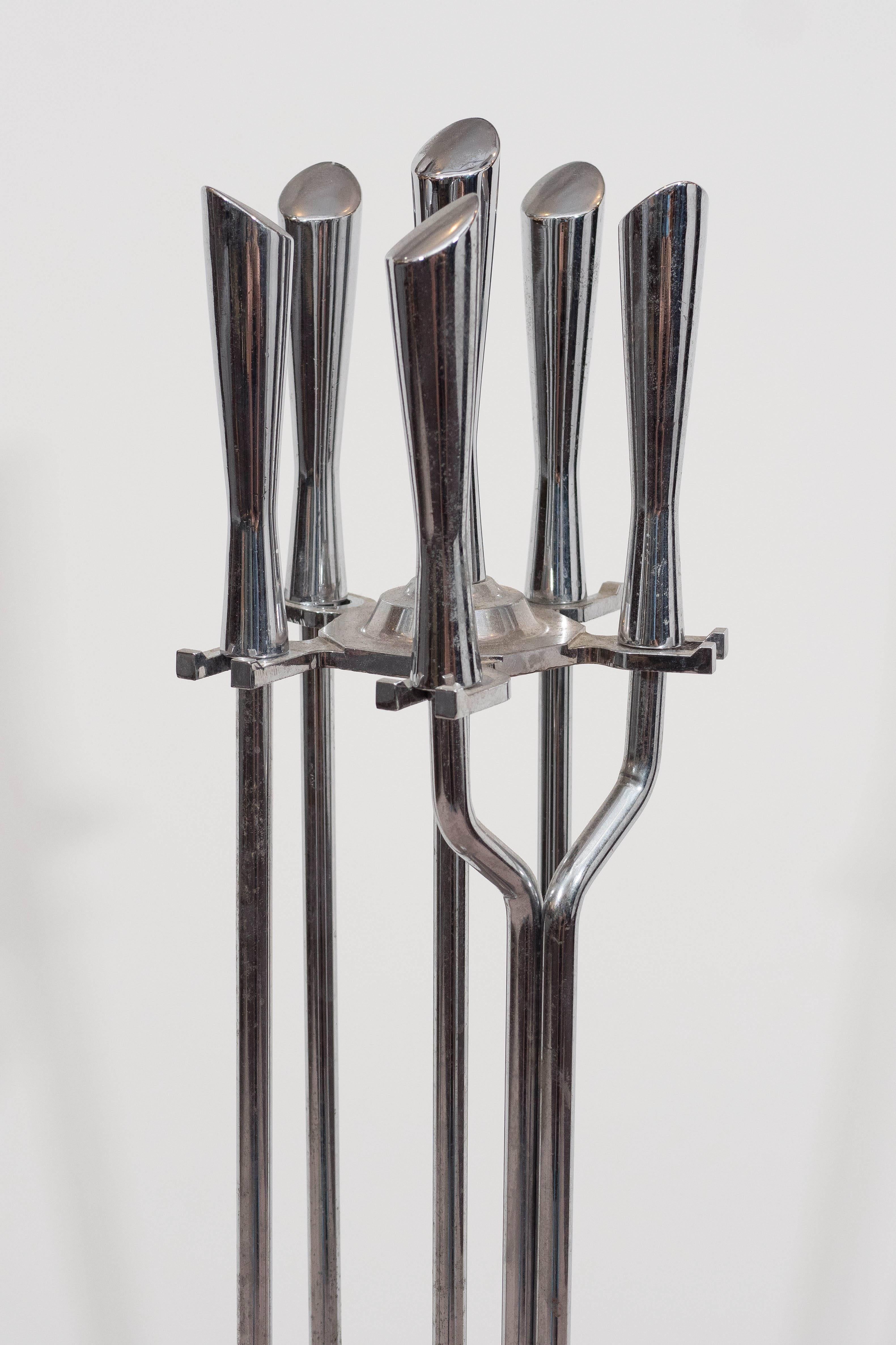 Set of fireplace tools, in chrome with unique bias cut handles include brush, pick, tongs and shovel affixed around a hexagon base. Good vintage condition, with minor wear to the chrome surface and slight fraying to the brush bristles, consistent