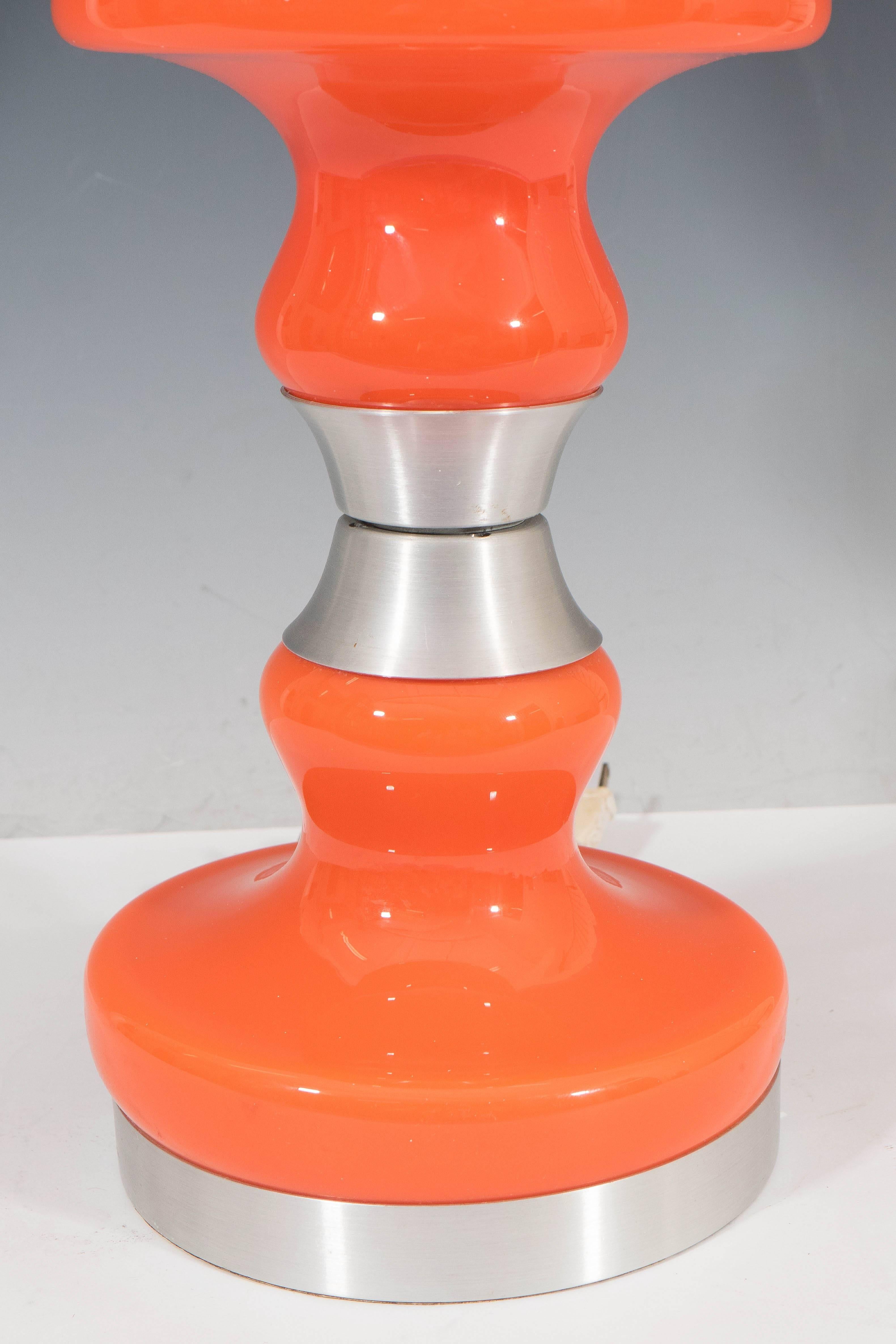 A vintage Italian glass table lamp, produced by Stilux, with white glass globe shade, above a bright orange baluster form body and banded detail in brushed aluminum. Markings include label [Stilux-Milano/Made in Italy], set to the top of the glass