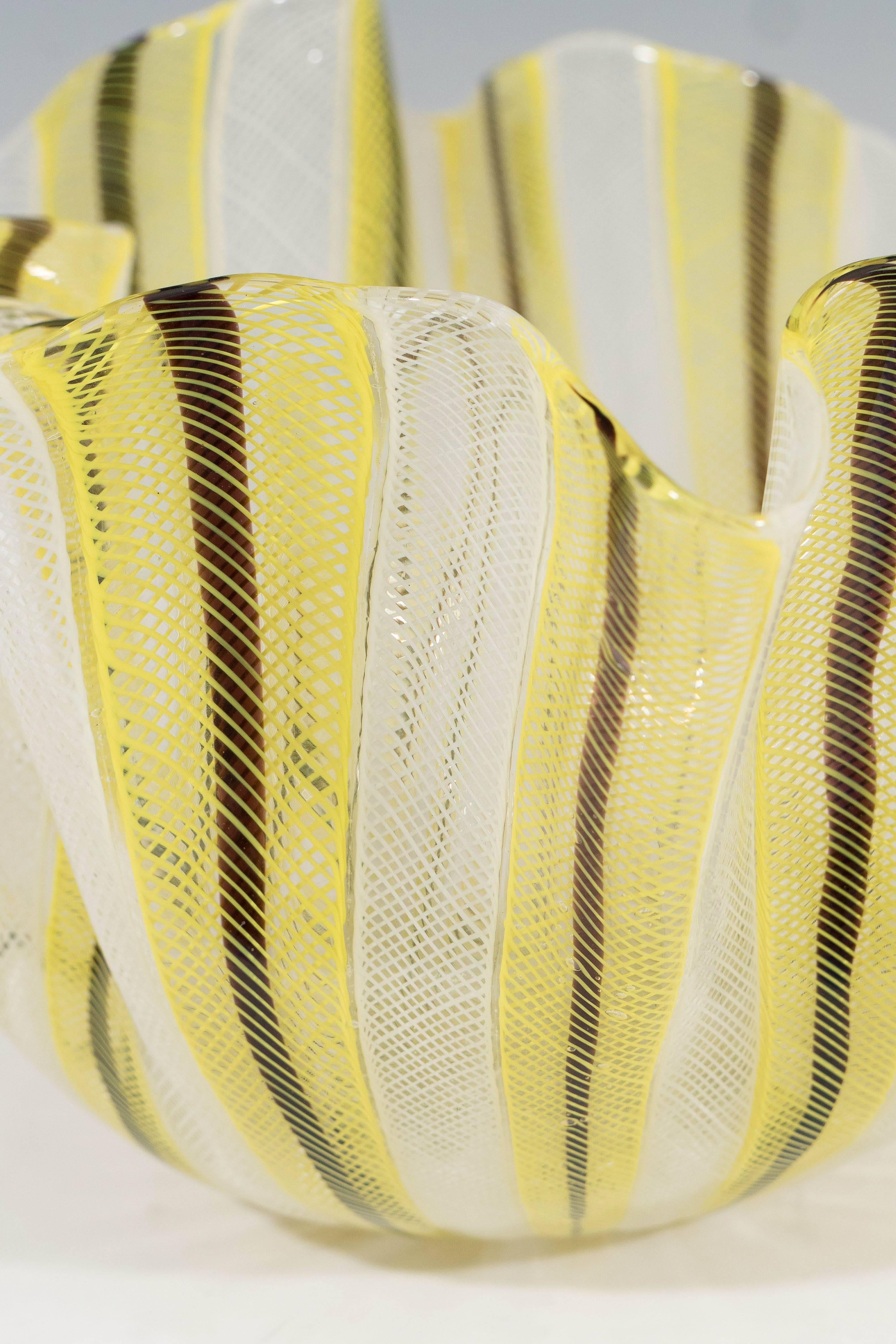 Paolo Venini and Fulvio Bianconi introduced the ‘Fazzoletto’ or ‘Handkerchief’ design in the late 1940s. This yellow and black version of the Handerchief bowl is made in latticino and zanfirico glass technique, to create the distinct cane-work