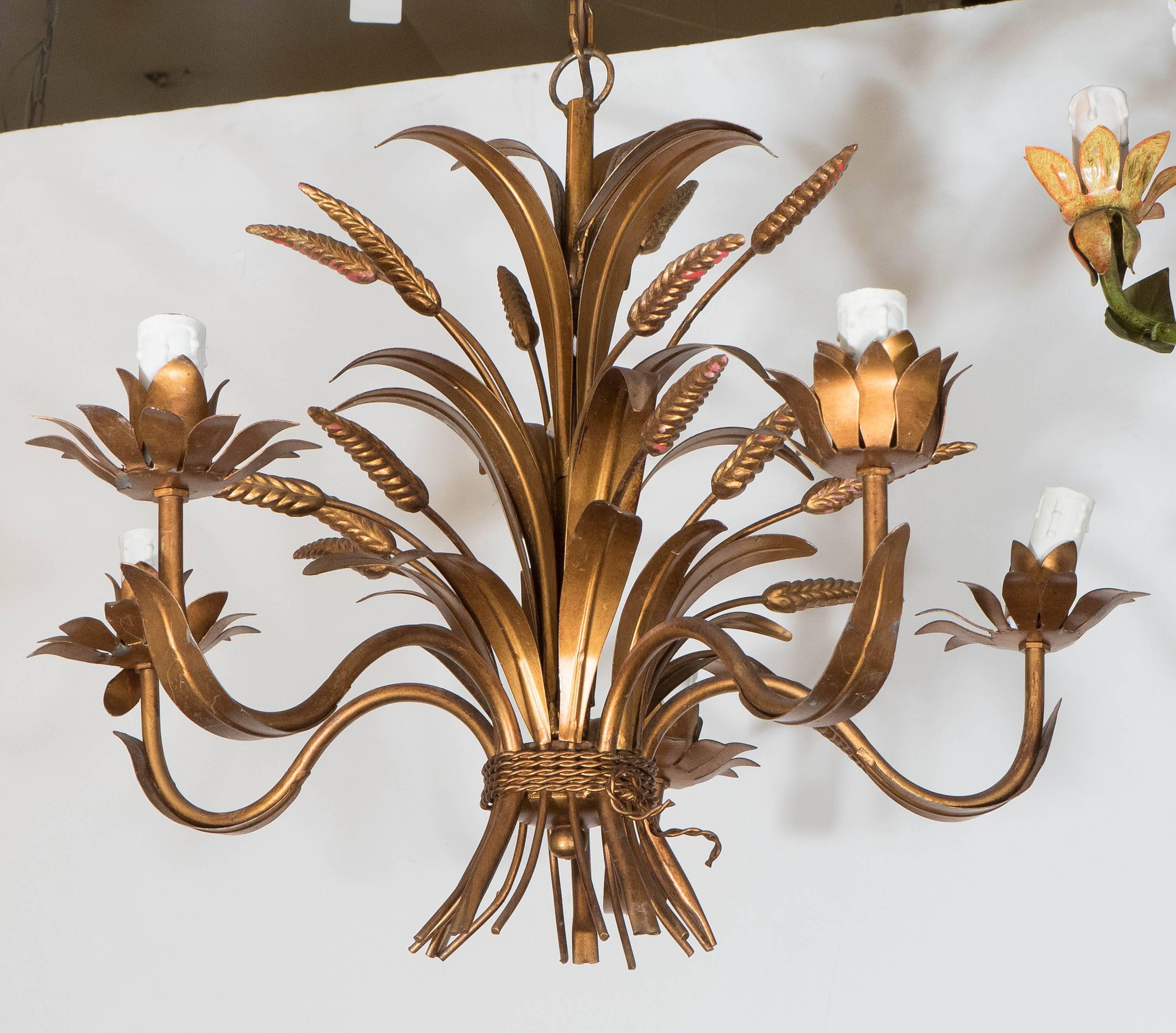 A vintage Hollywood Regency style five-arm chandelier, produced in France, circa 1960s, designed as an elaborate shaft of bound wheat and leaves, in gilt metal; includes socket covers with faux dripping wax. Wiring and sockets to US standard,