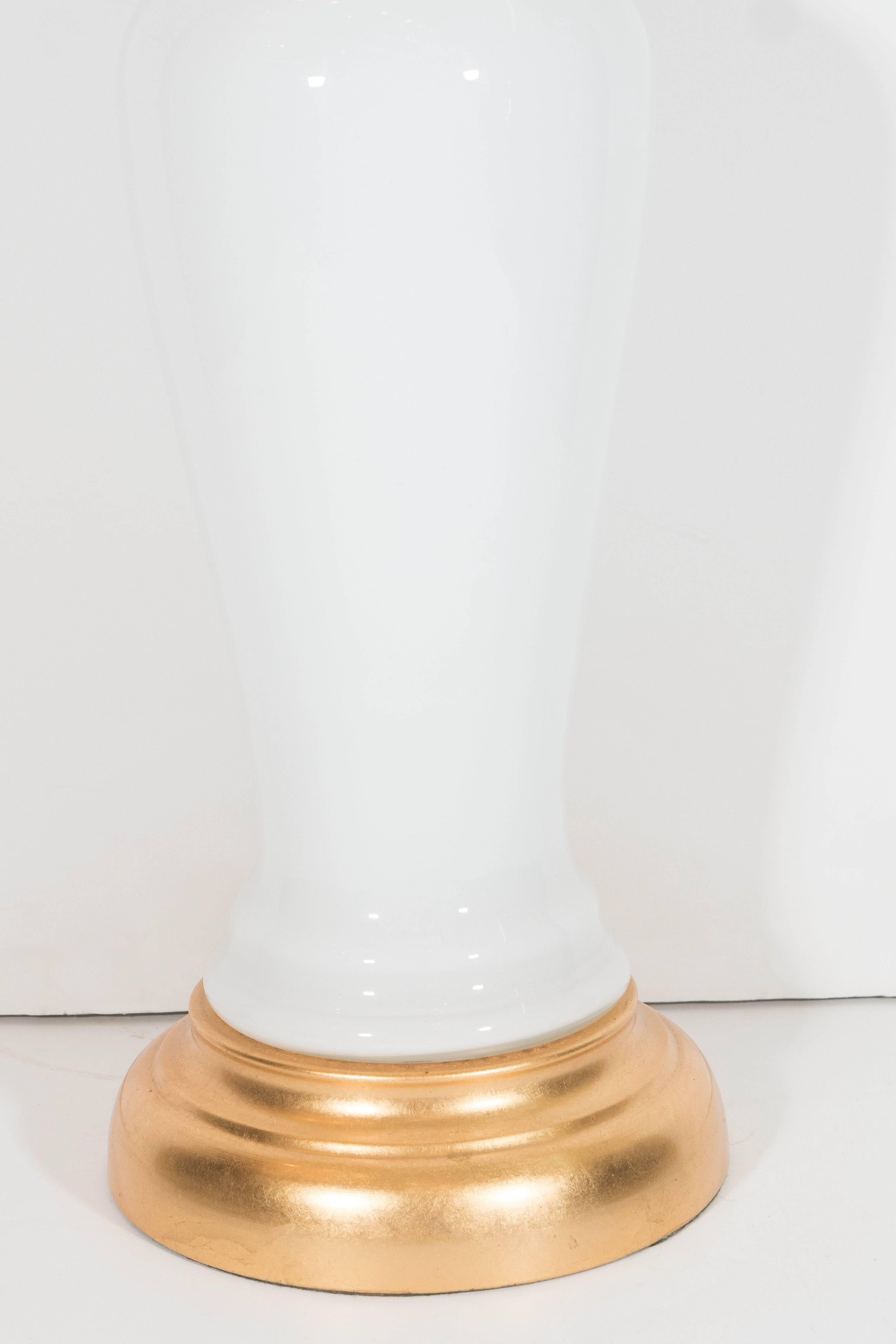 A pair of vintage white opaline glass lamps, each including a single socket, with baluster form bodies on gilded bases. Wiring and sockets to US standard, each requires a single Edison base bulb. Dimensions reflected do not include the shade. Very