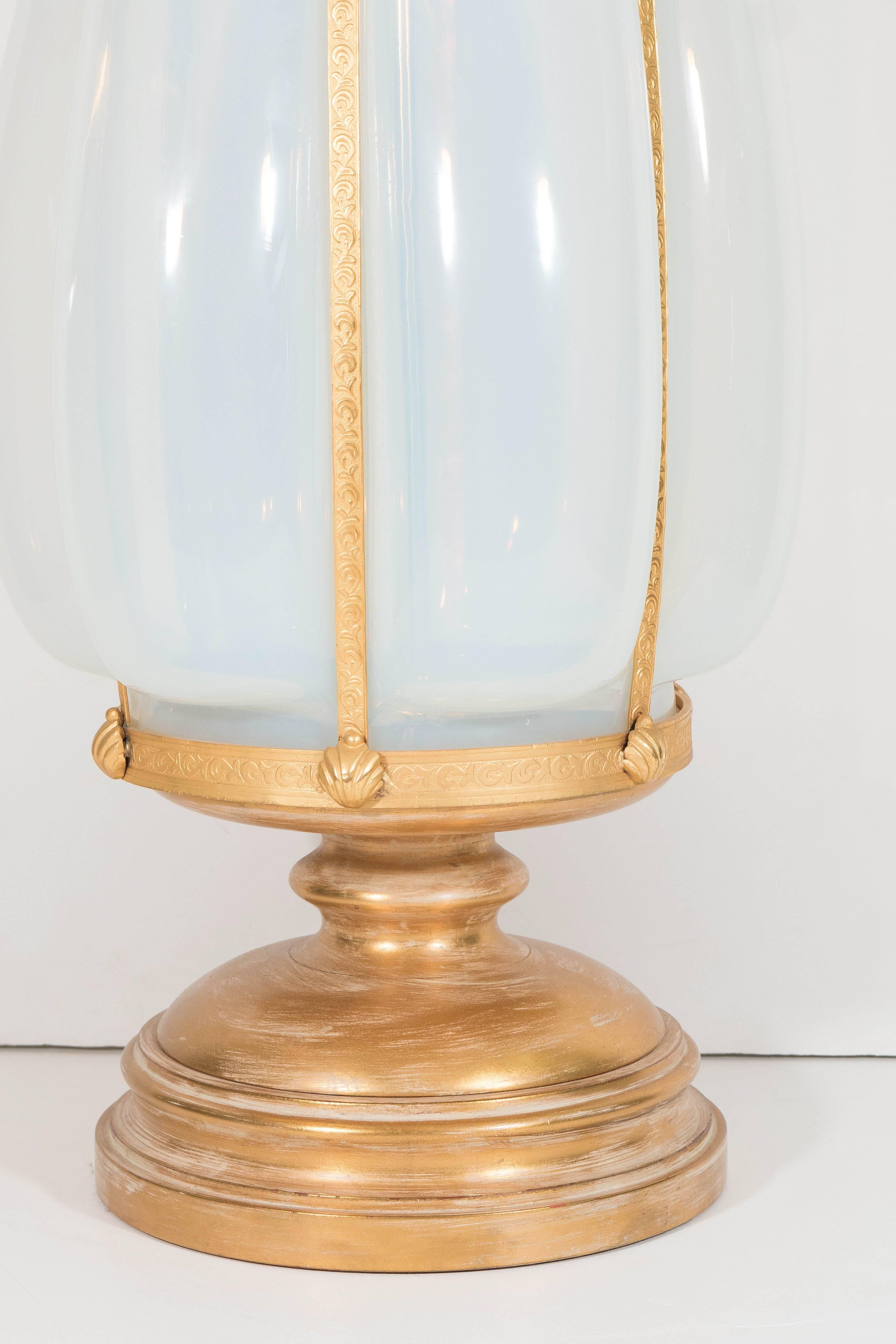 A vintage large-scale Italian table lamp, produced circa 1950s, featuring the original pointed finial, surmounting an opaline glass body, inset within gilded mounting, detailed with acanthus leaves and shells. Wiring and sockets to US standard,
