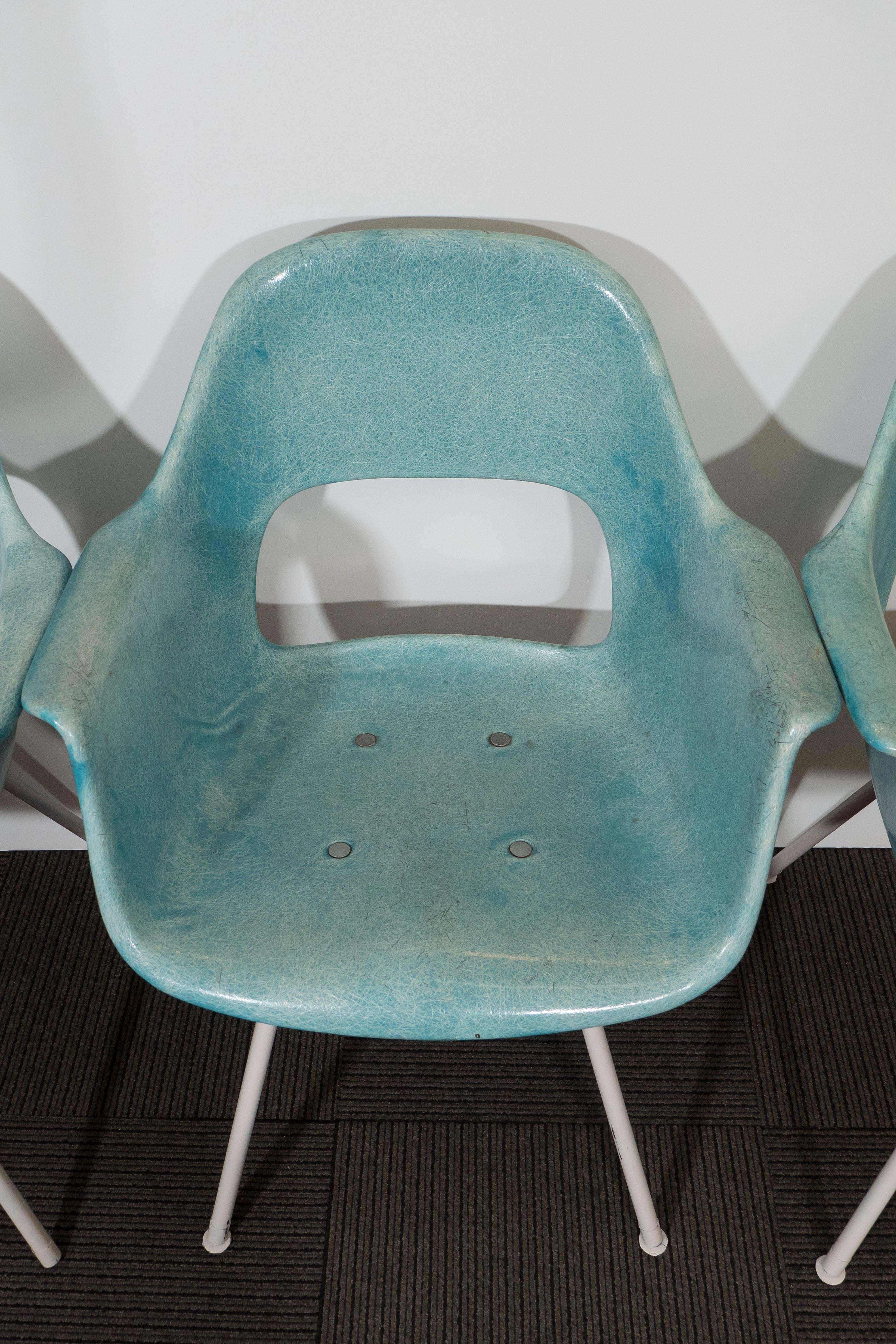A beautiful set of five turquoise armchairs, in the style of the iconic Zenith design by Charles and Ray Eames, originally created in the 1950s. Each chair features a molded fiberglass seat, with metal accents, and the legs finished in white paint.