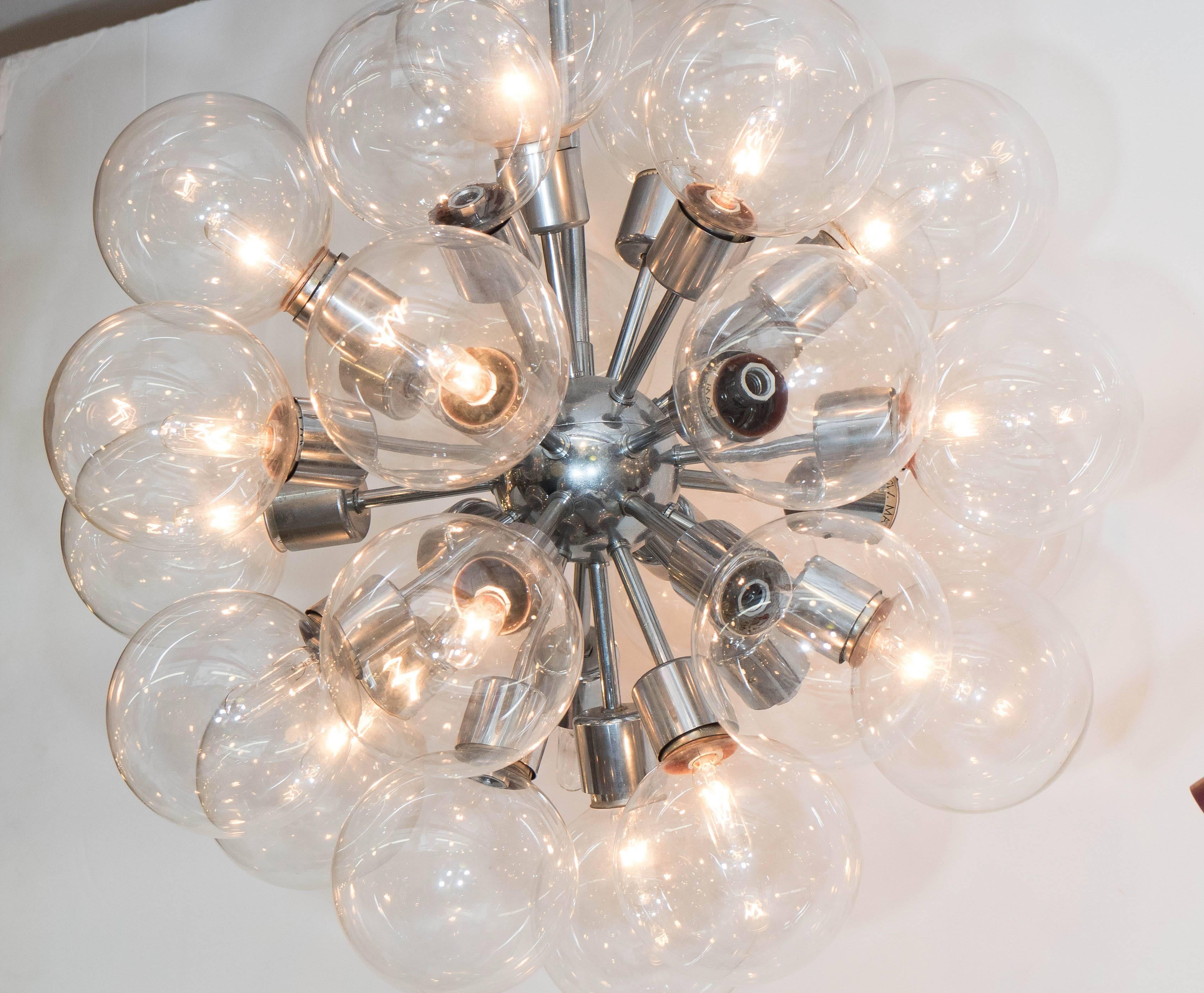 A vintage Sputnik chandelier, produced circa 1950s by Lightolier, with polished chrome frame, each radiating stem terminating in a socket, surrounded by a glass globe shade. Wiring and sockets to US standard. Good vintage condition, with minimal age