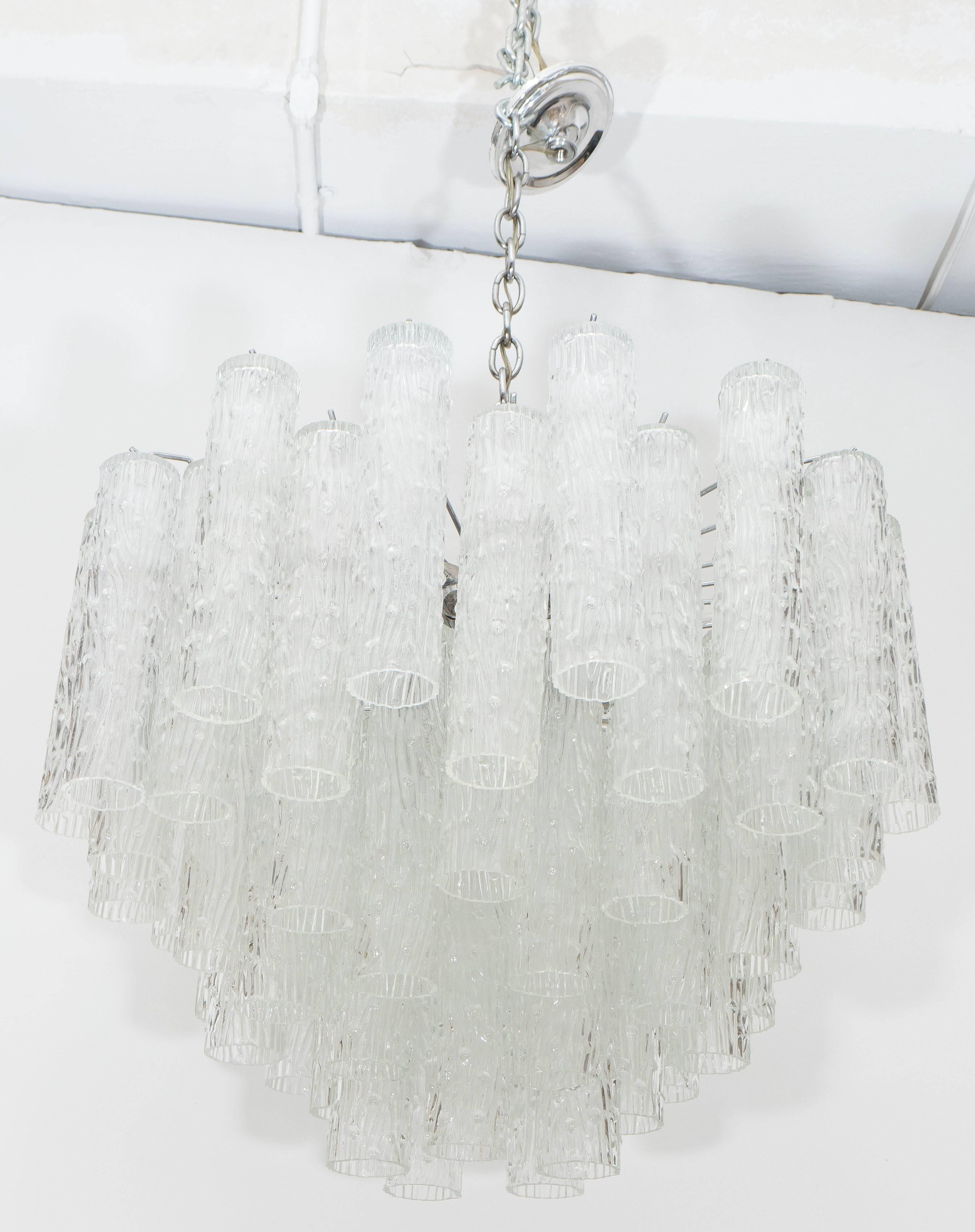 A vintage highly modernistic chandelier, produced circa 1960s-1970s, surrounded by staggered textured glass tube prisms, suspended from a chrome frame. Requires 16 candelabra base bulbs. Very good condition, consistent with age and use; dimensions