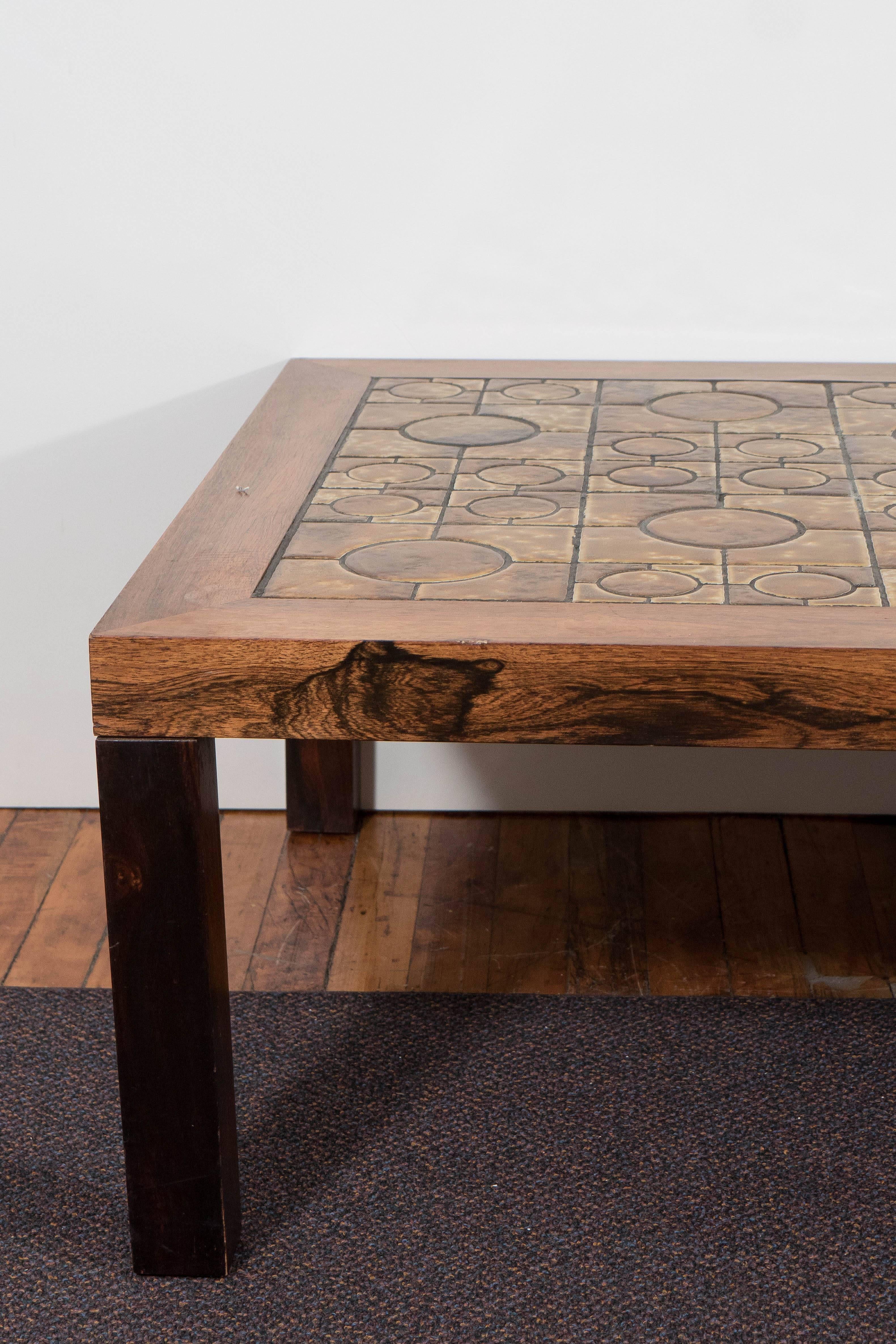 A Danish coffee table, produced by Centrum Møbler, with clay tiled top, inset against a rich wood frame. Markings include manufacturer's sticker label, [C.M./Centrum Møbler/Ringsted/Made in Denmark]. Good condition, with some staining to the wood