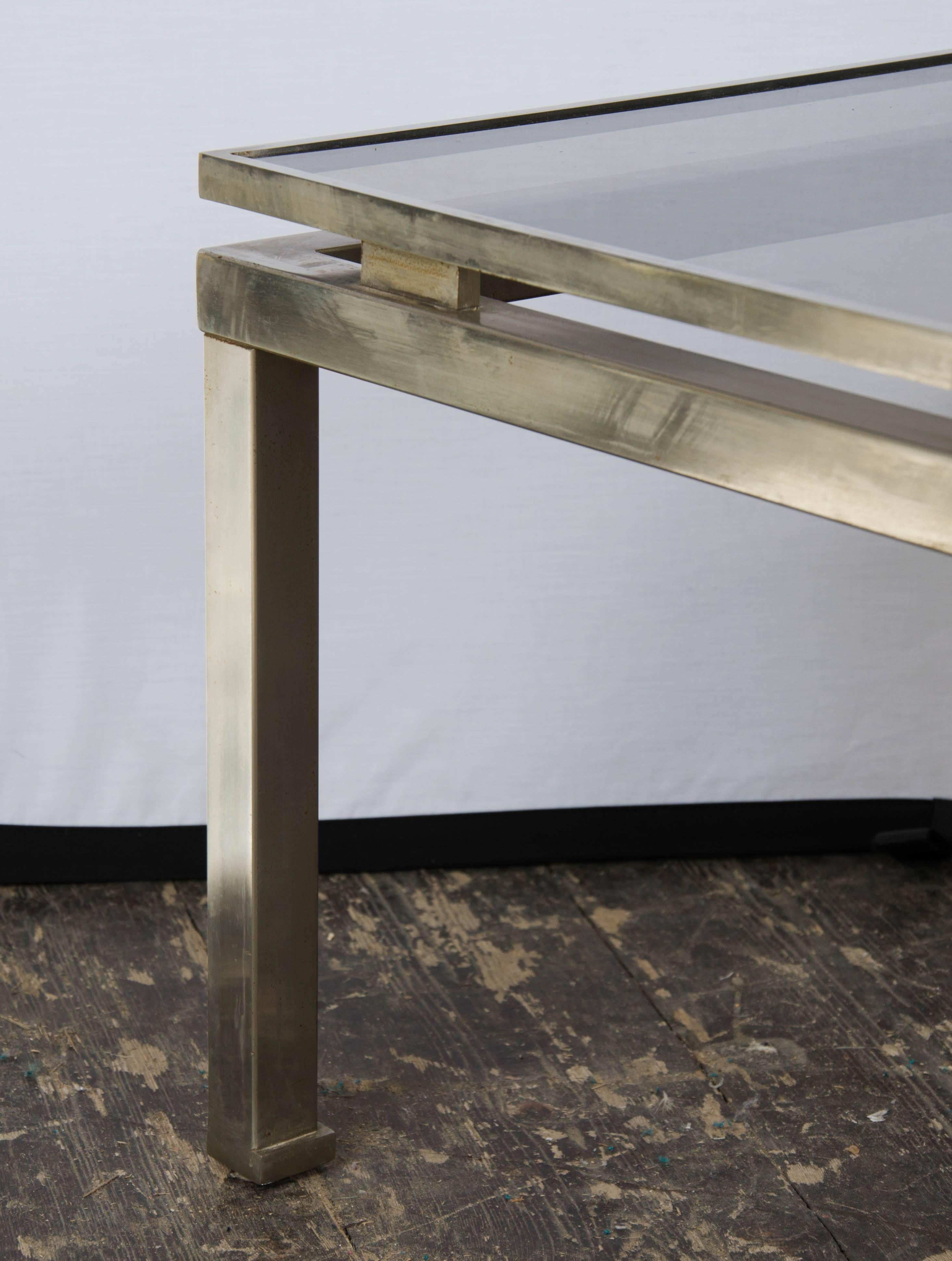 A pair of vintage side tables in antique polished steel and smoked glass tops, designed by Guy Lefevre, 1960s, French.