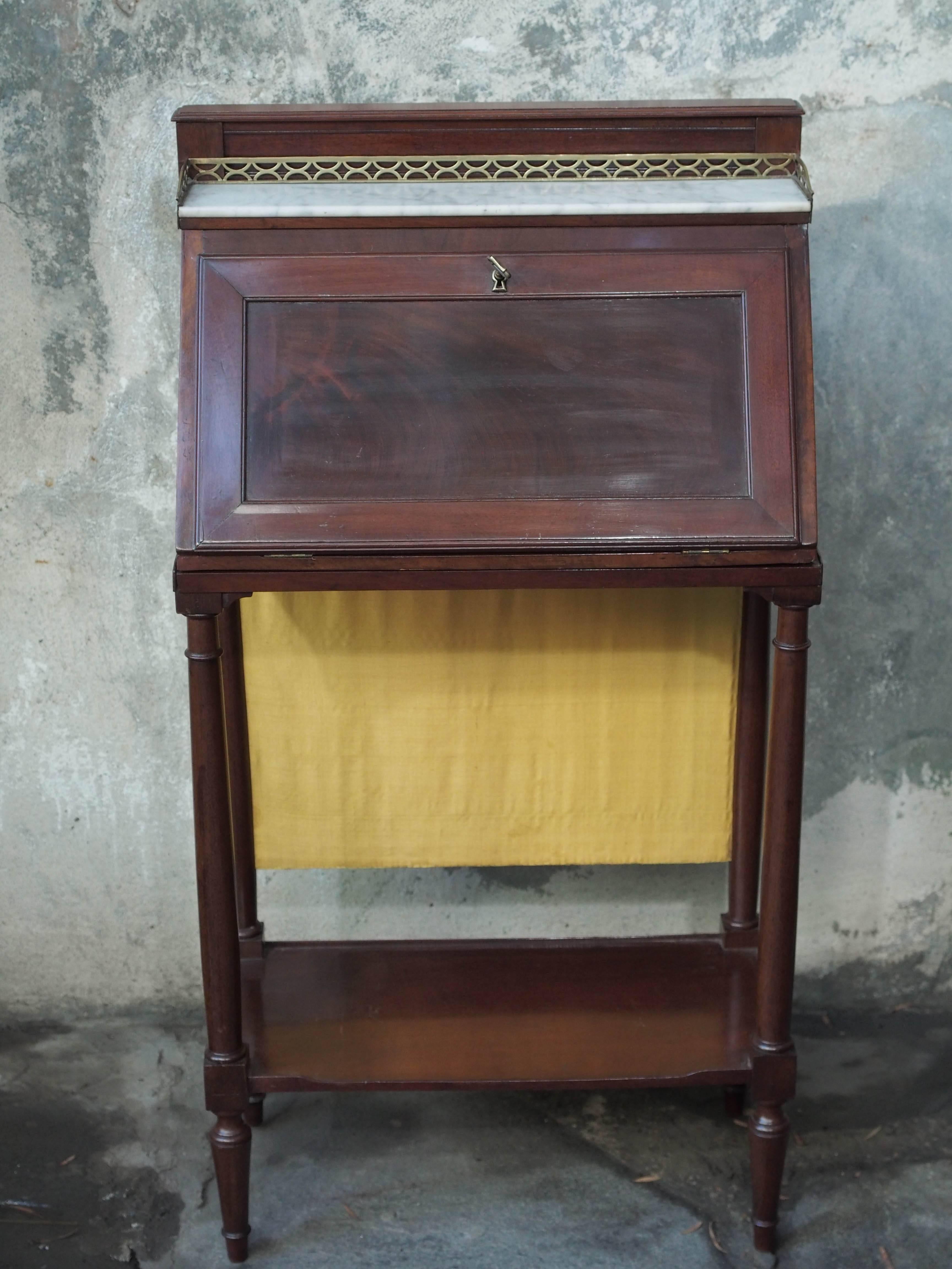 Unusual and small-scale French Directoire/Empire transition period mahogany drop front desk, with white marble top with brass gallery, removable from stand with fabric back and white marble shelf.