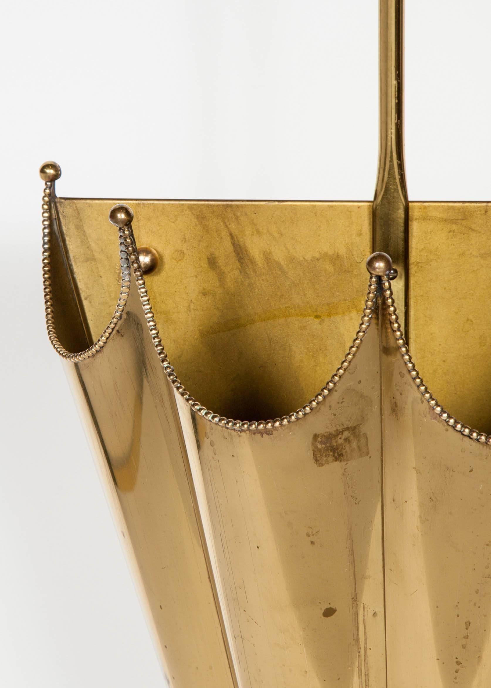 Elegant mid-century modern umbrella stand with footed parasol design. Features chain ball trimming along the upper rims, with brass ball finials along the peaks. Evident signs of patina throughout the brass frame, contribute to the charm of the