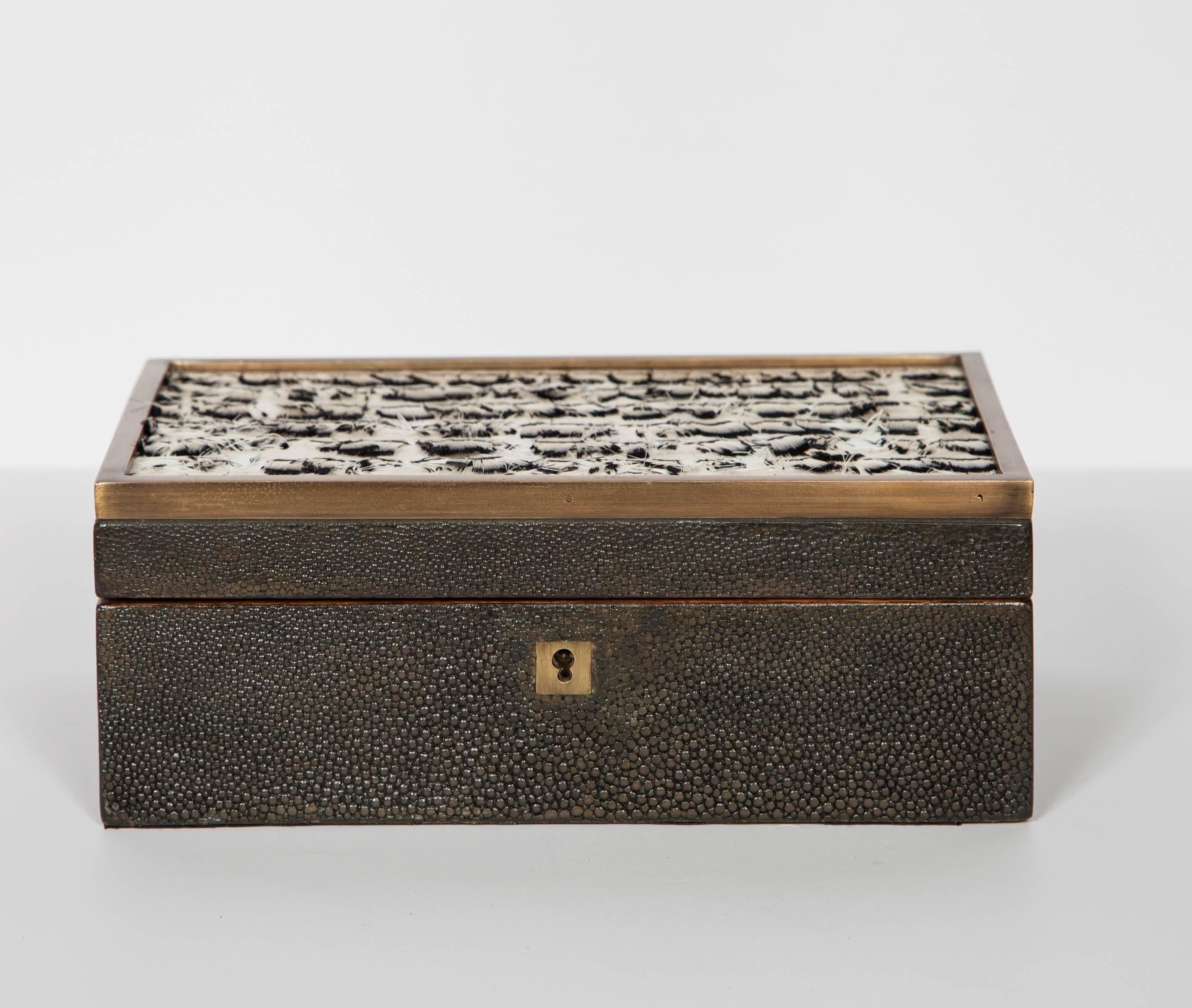 Jewelry box or decorative box in genuine stingray with speckled feather accents. Features hand-dyed shagreen in charcoal grey and hand-forged bronze trim details. The interior of the box is made of palmwood and is fitted with a removable black
