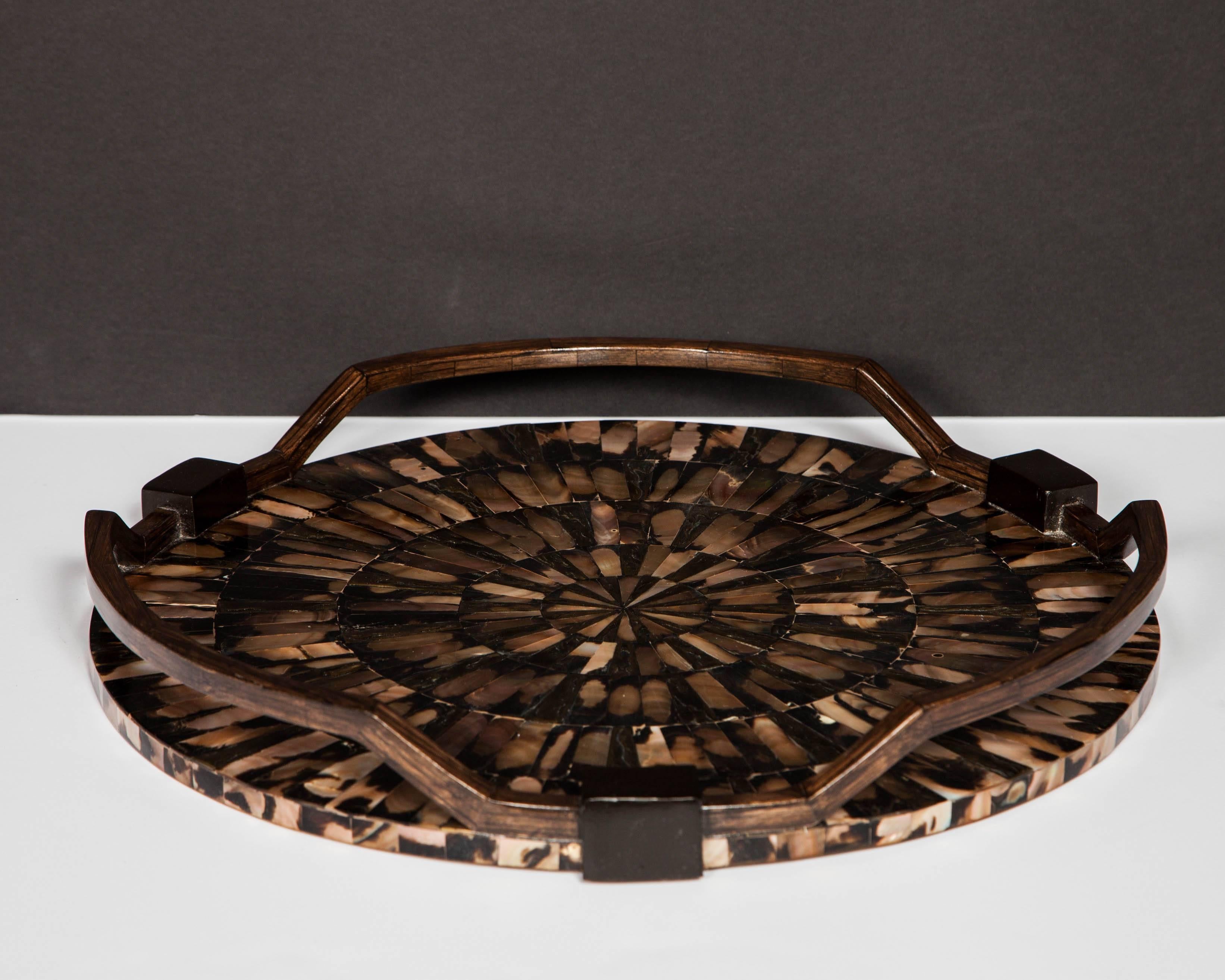 Outstanding round serving tray featuring exotic inlays of mother-of-pearl in varying iridescent hues.  The tesselated inlays create a spectacular starburst design.  All hand crafted, with a series of hand carved handles in palmwood with ebonized