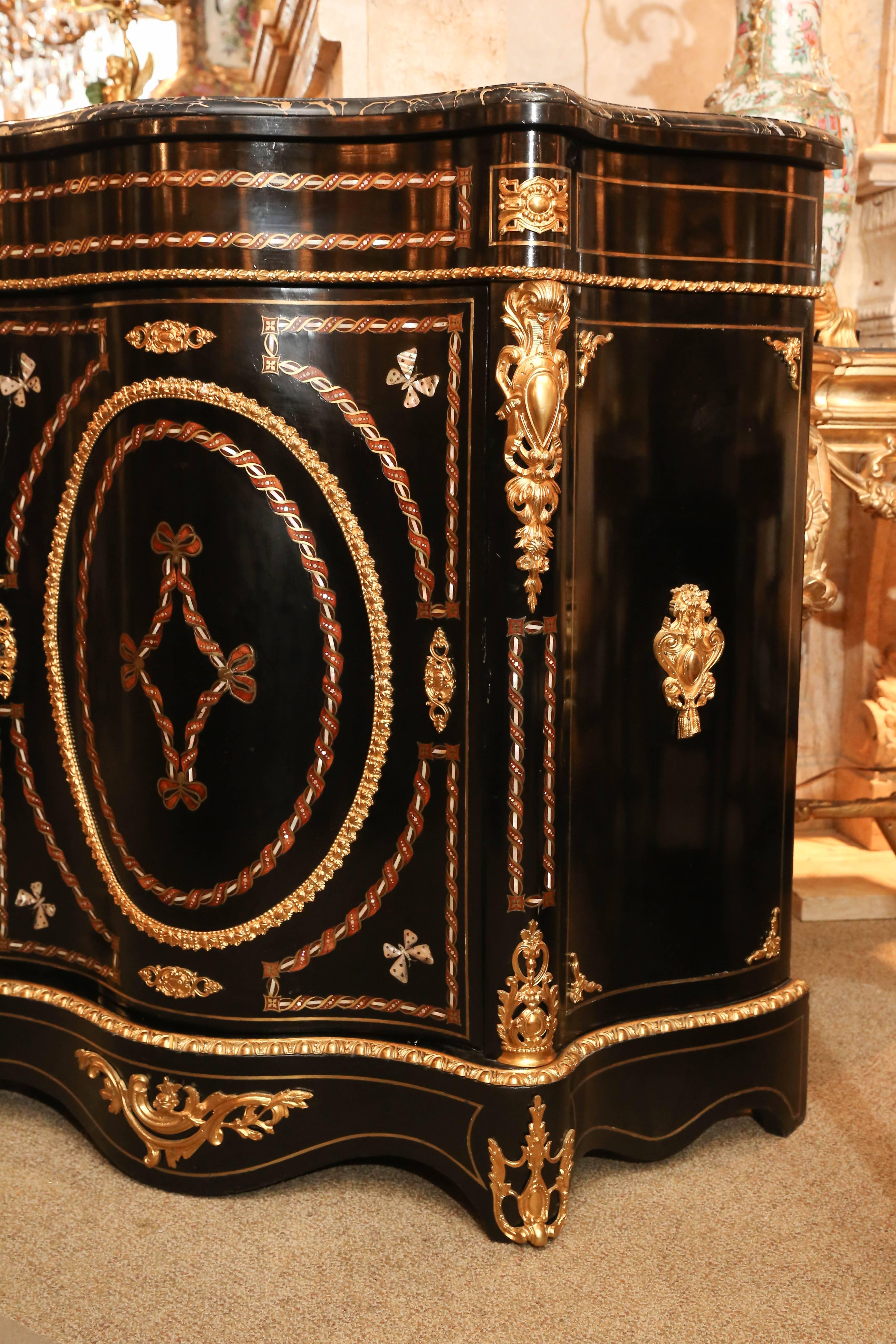 Porter noir des Pyrenees marble top above a conforming cabinet with a center door opening to a shelved and mahogany -lined interior, exterior is ormolu
Mounted and inlaid mother of pearl, a ahoy and boulle stringing, mother of
Pearl butterflies to