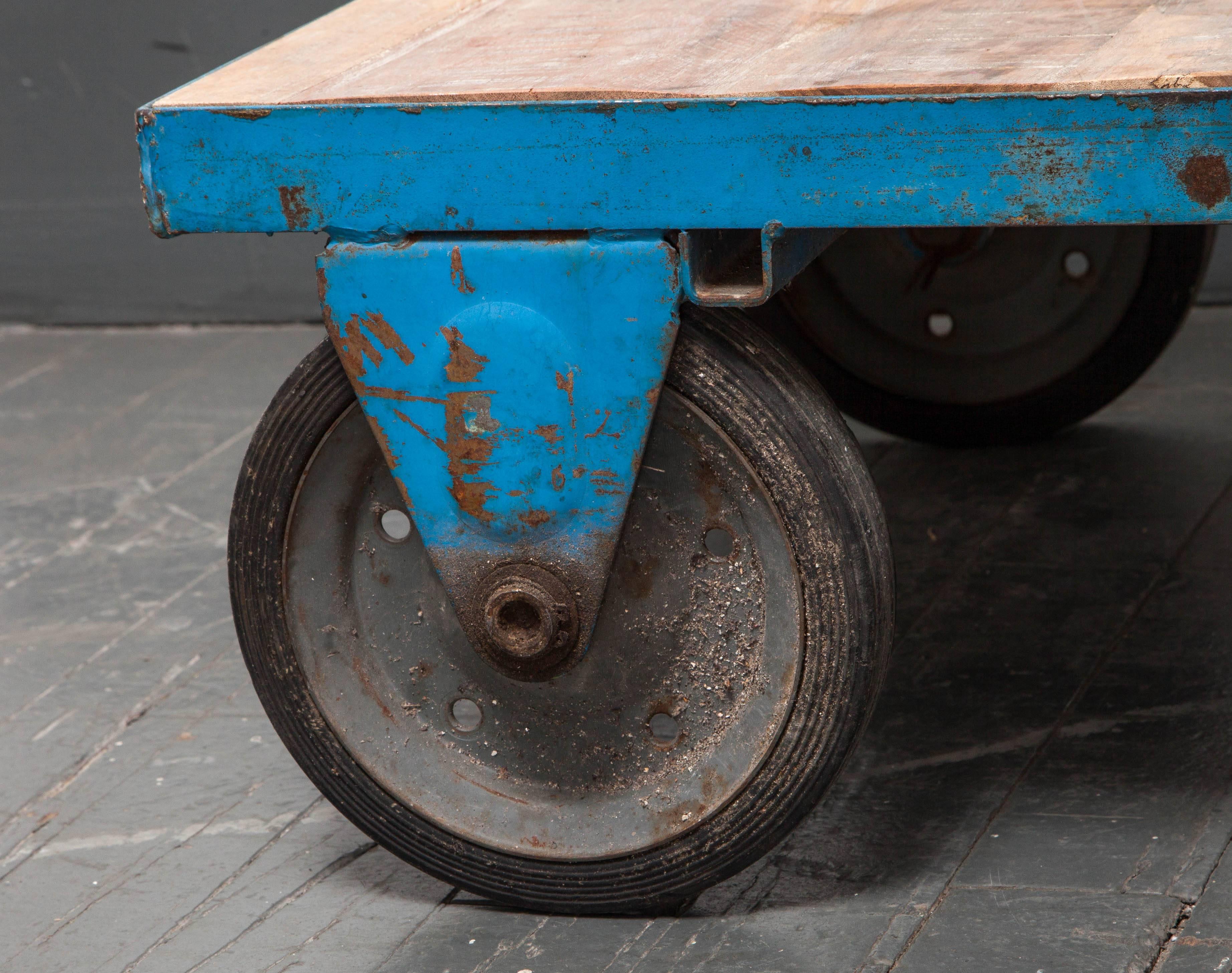 Industrial cart table on wheels, painted metal base with wooden top.
