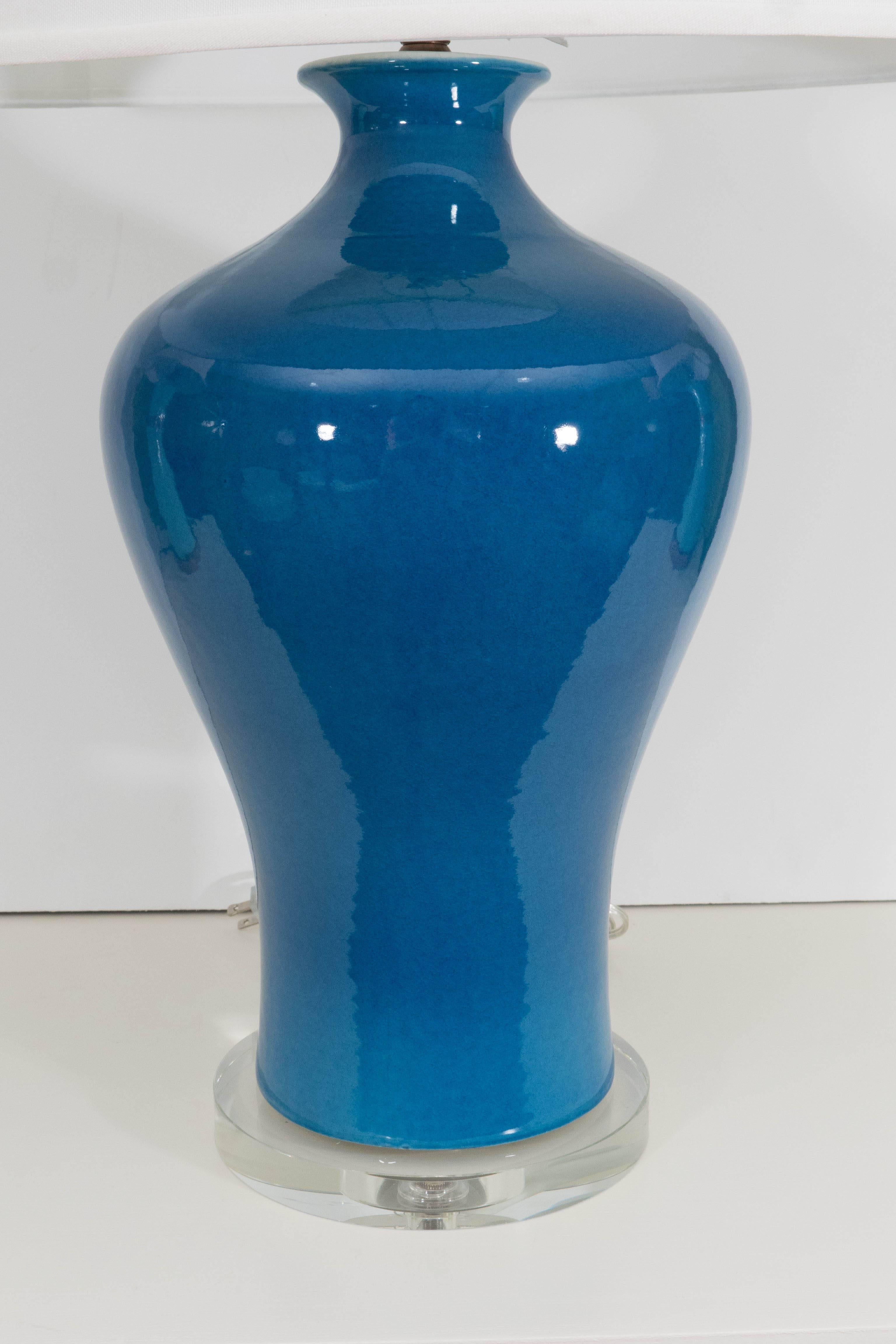 A large Chinese porcelain vase in a stunning blue converted to a lamp on a glass base with shade.