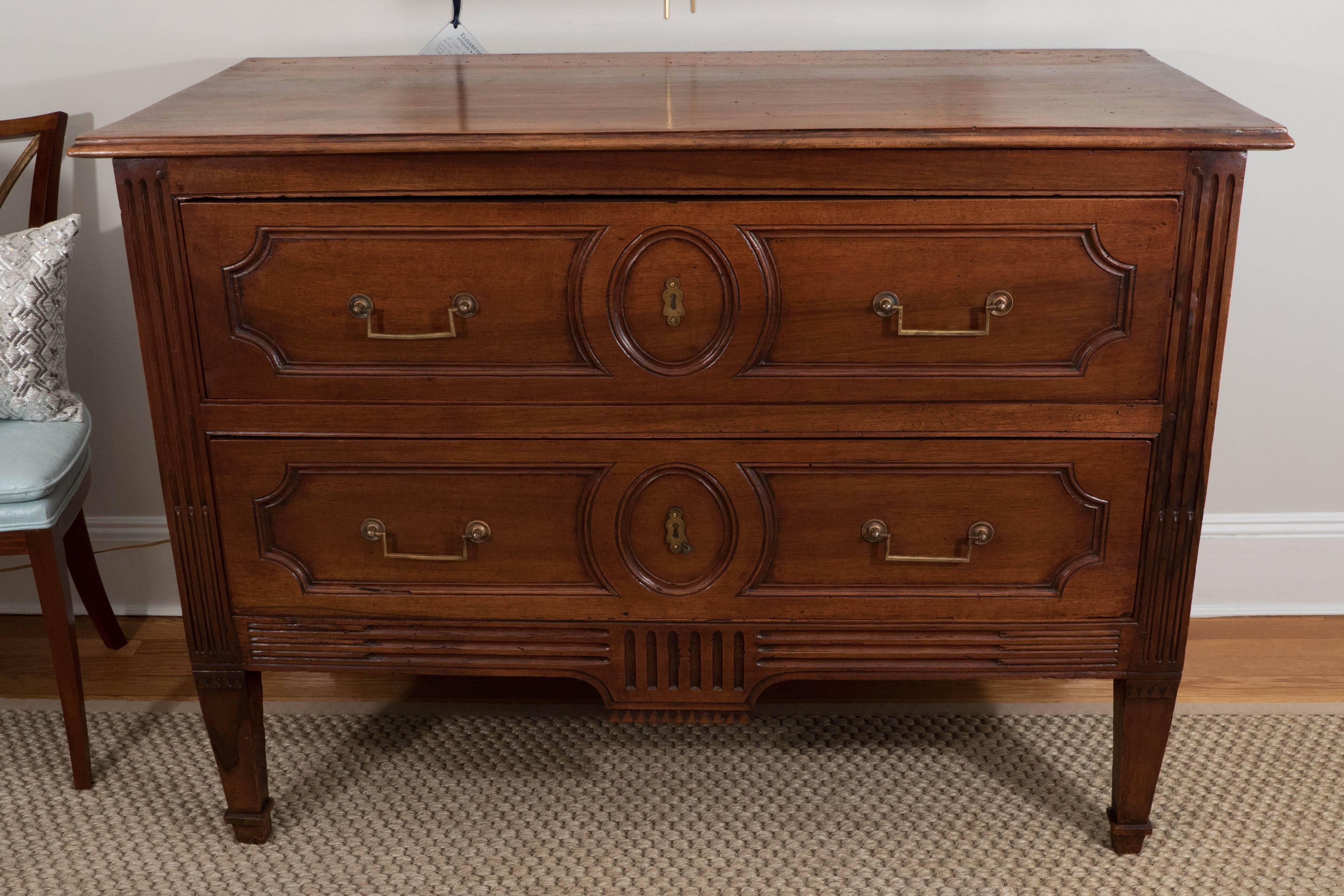 A piece of exceptional quality, this solid walnut commode has two drawers with bronze fittings, reeded side columns and apron, inset panels on front and sides, raised on tapered legs. A true beauty.