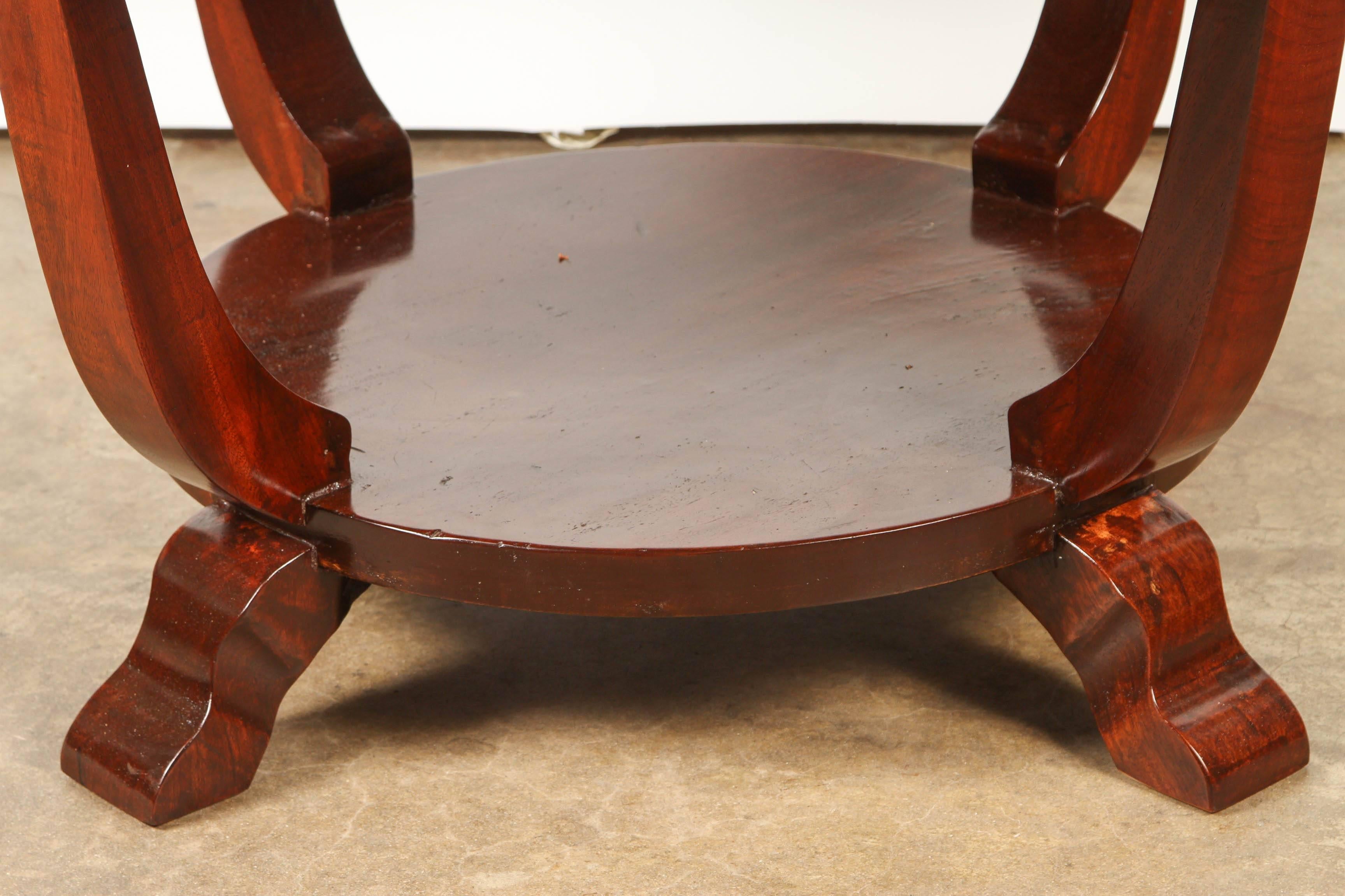 Made for the local French market, this Vietnamese solid rosewood table has a charming and slightly primitive take on the Art Deco Style. A circular top is supported by 4 gently curving legs, with a lower shelf supported by 4 feet.