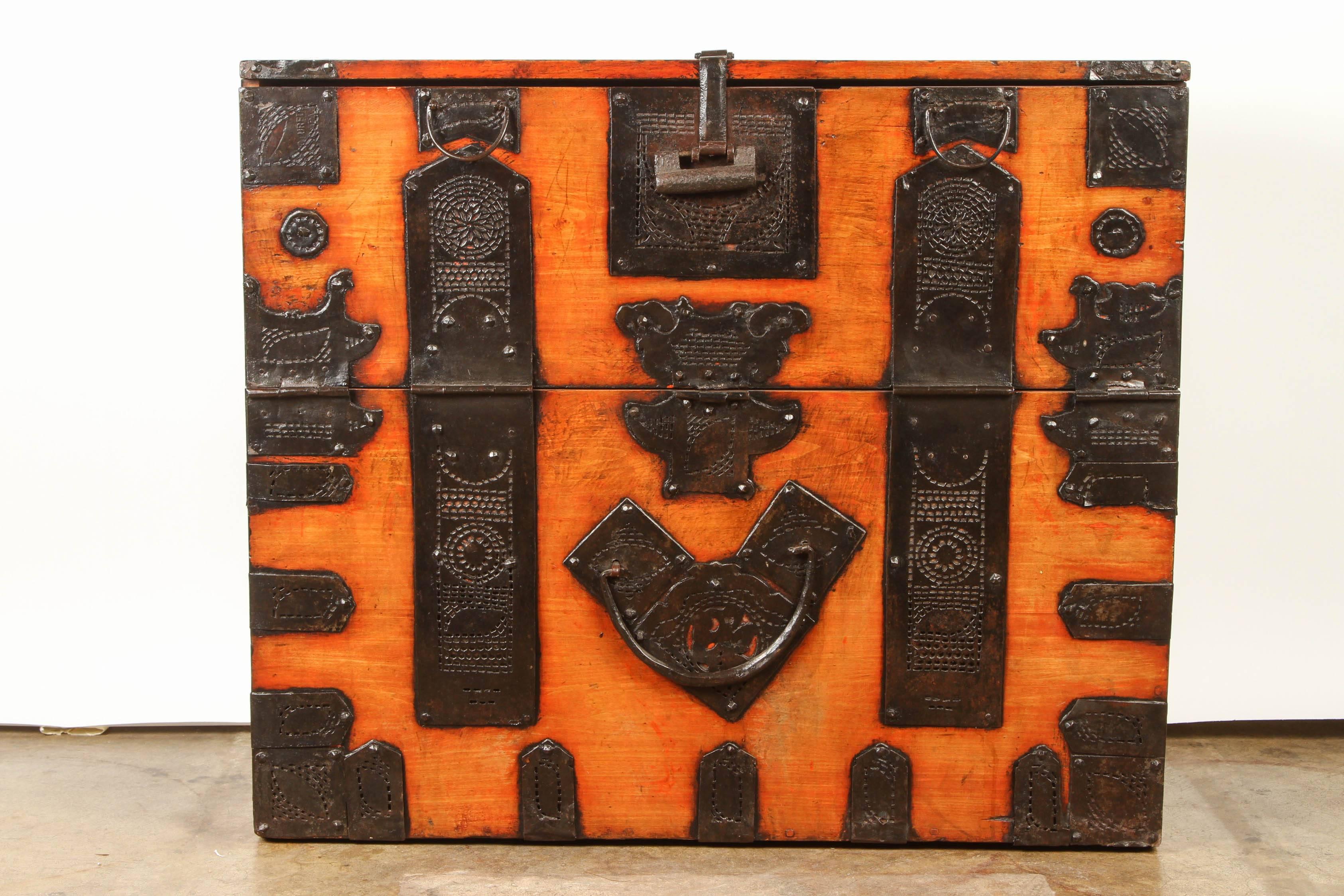 Korean drop front chest. The original dark lacquer has mellowed to an attractive orange and red. Covered with black metal strapping and decorated metal.