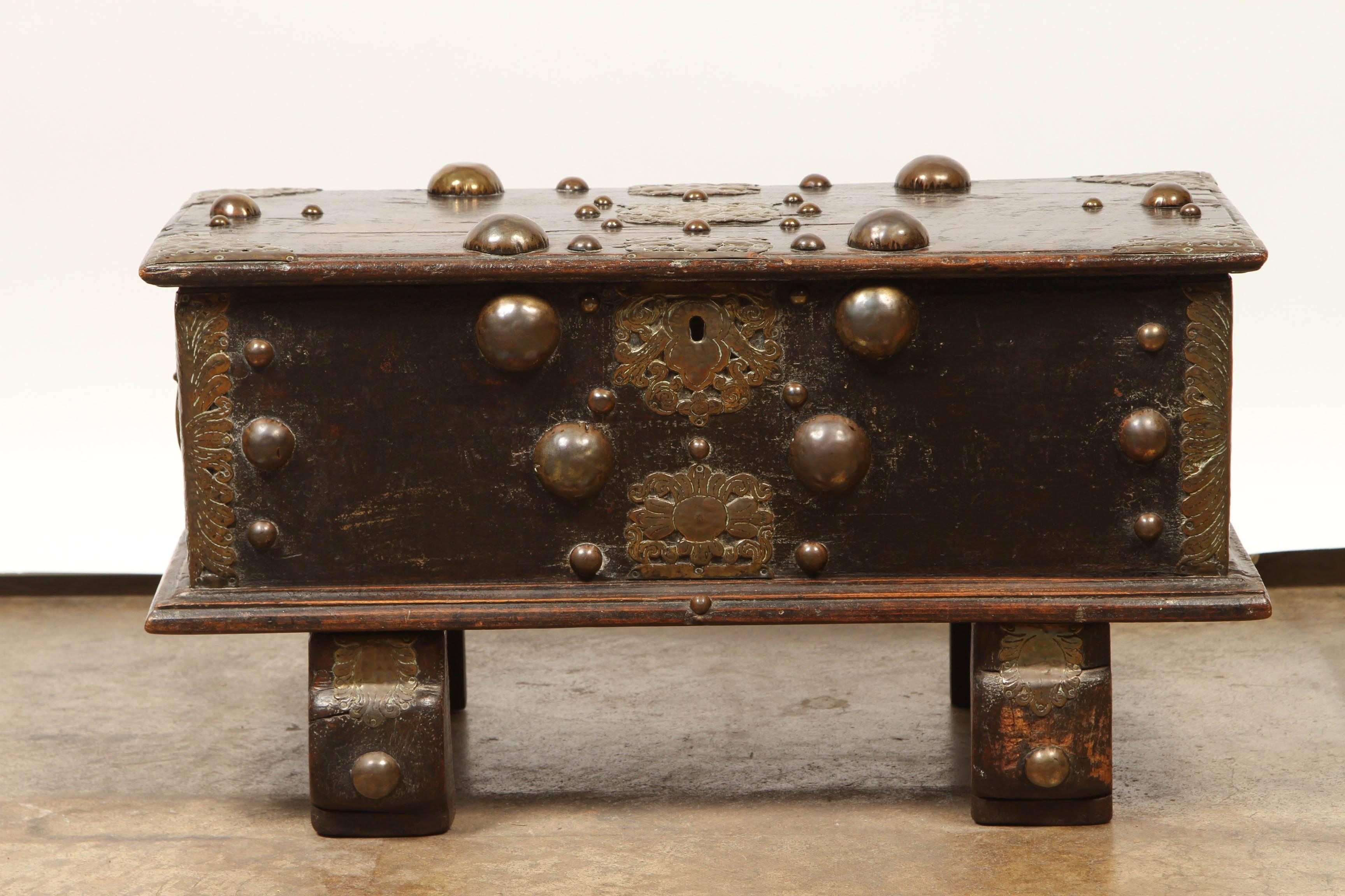 Dutch Colonial, from Ceylon (now Sri Lanka). Deeply Patinated Jack Wood decorated with Brass Caps, overlay and straps, on a pair of strut feet.