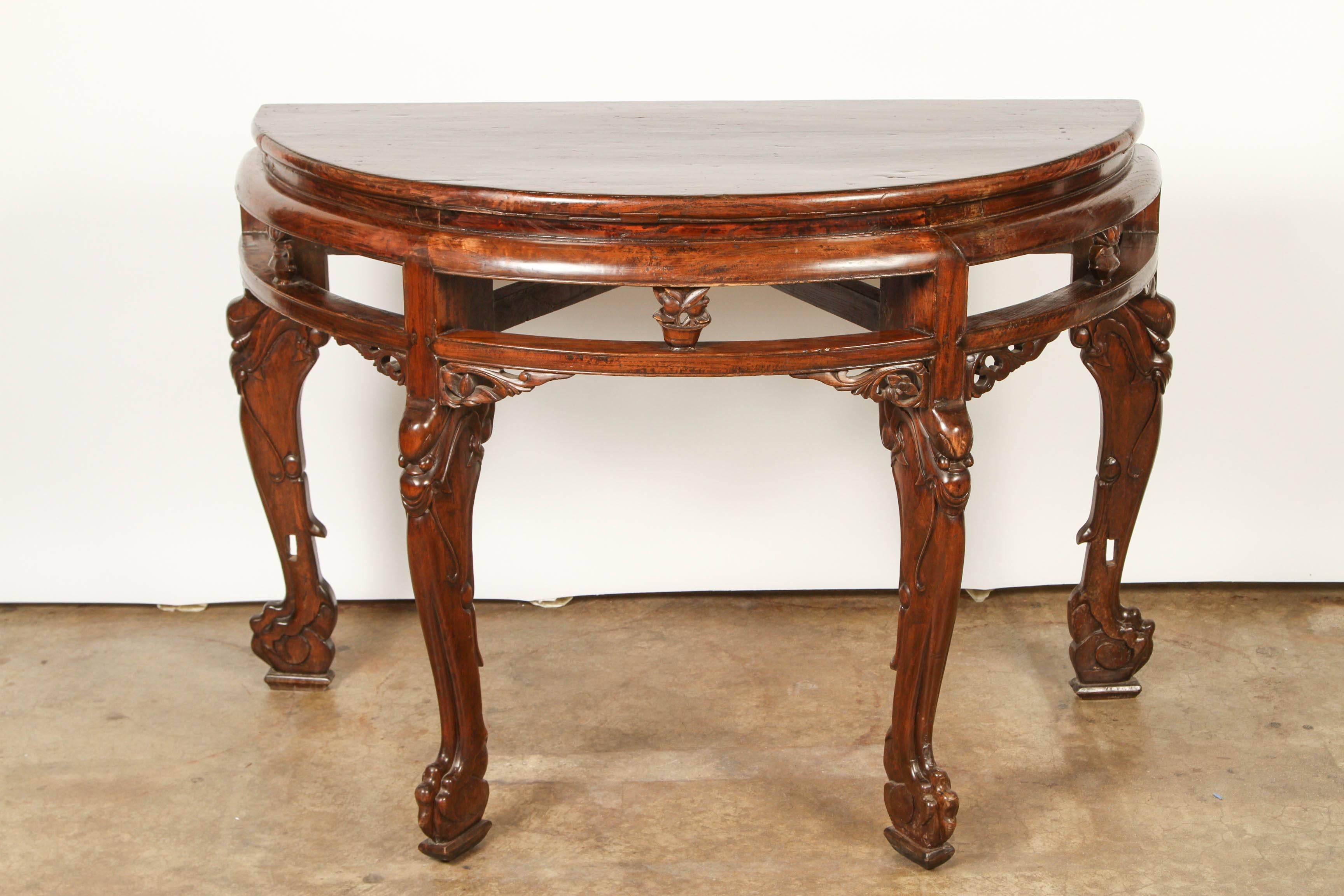 A pair of handsome Chinese demilunes. They can be placed back-to-back to create a single center table. They have carved legs that depict dragon faces and legs.