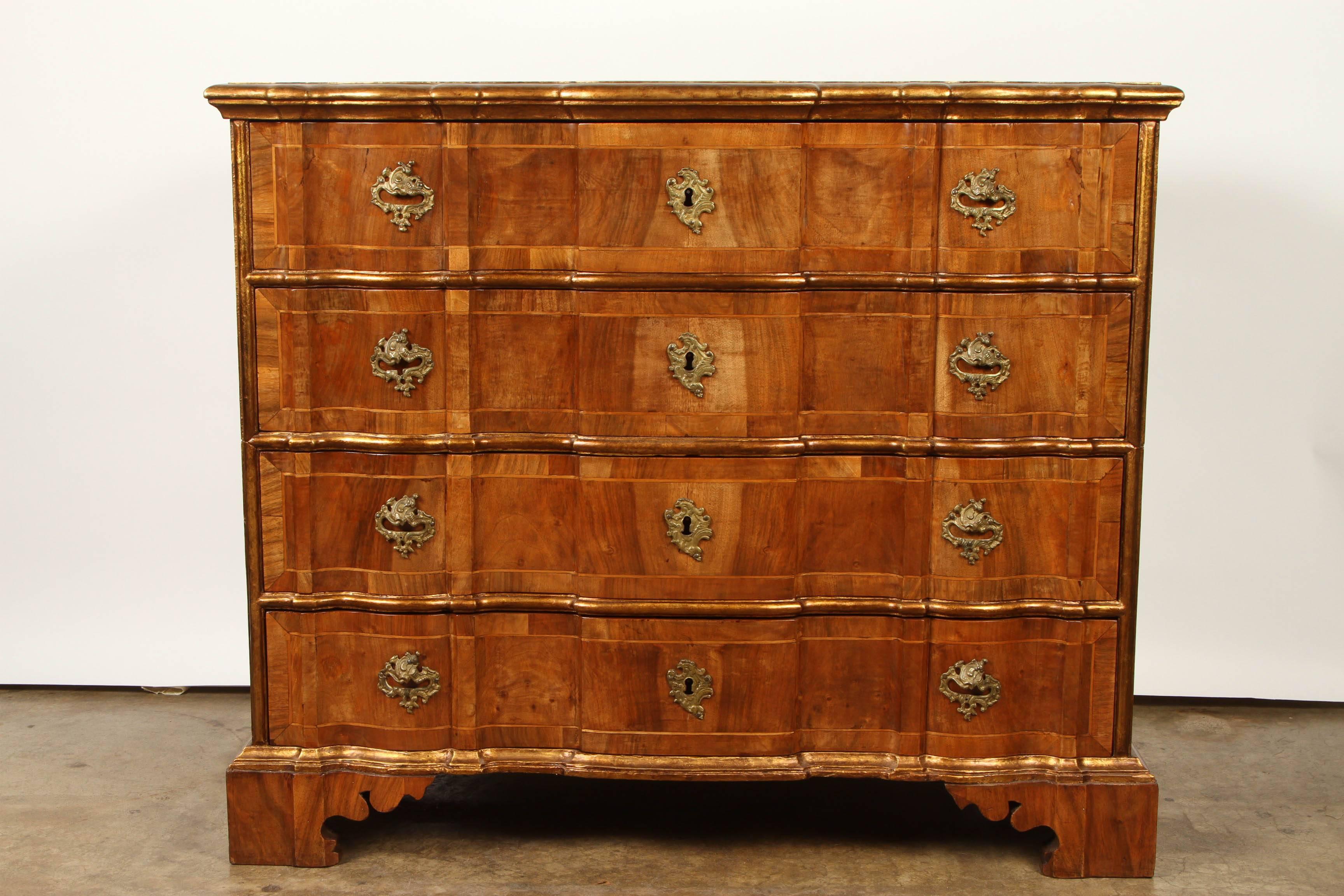 A Danish Rococo chest of drawers, consisting of four drawers, with gilt bronze hardware and gilt borders. This Danish chest is veneered in walnut and has banding on each drawer.