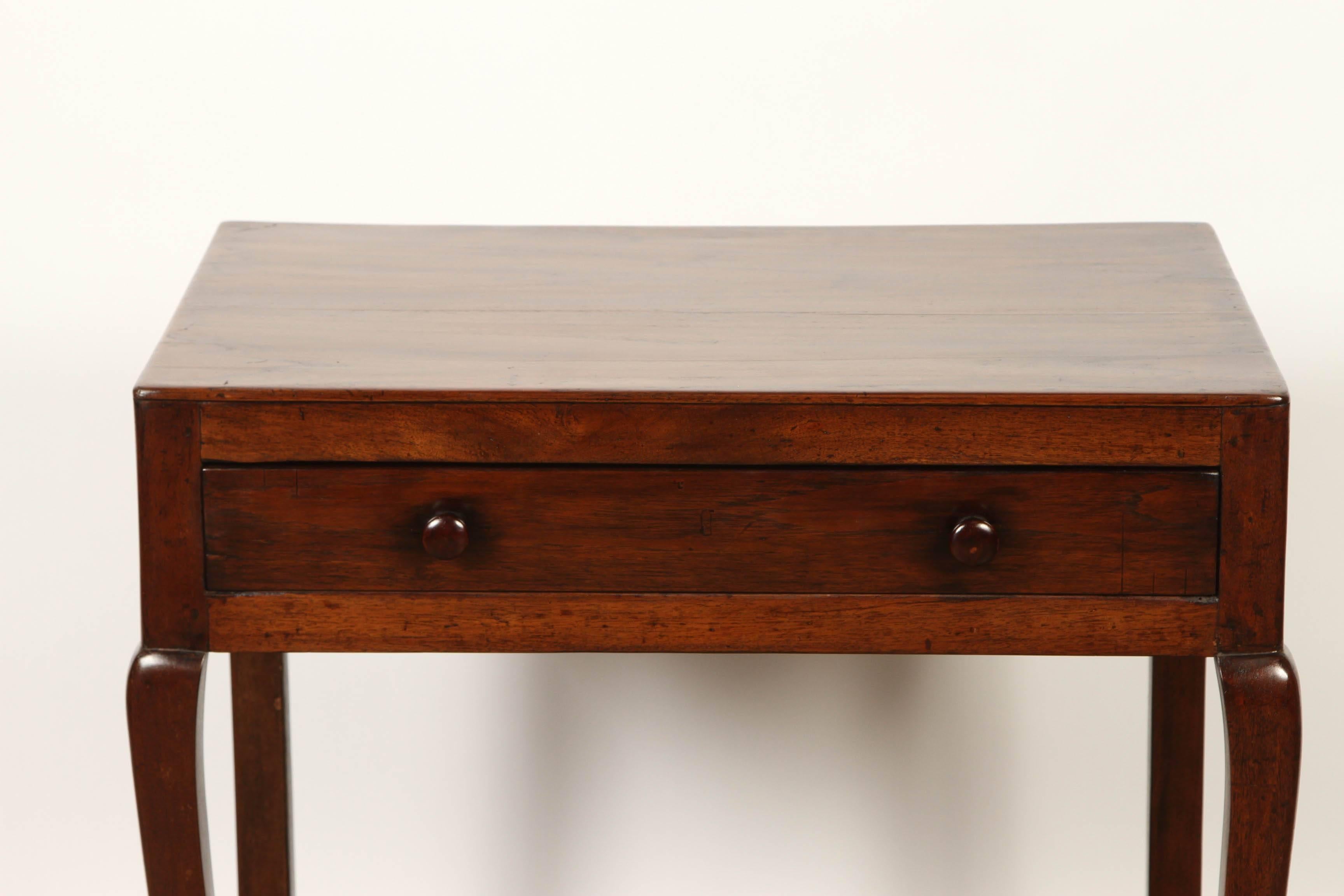A French Colonial rosewood side table, which is simply constructed of solid rosewood with a single drawer that has two pulls, and a shelf underneath. 
