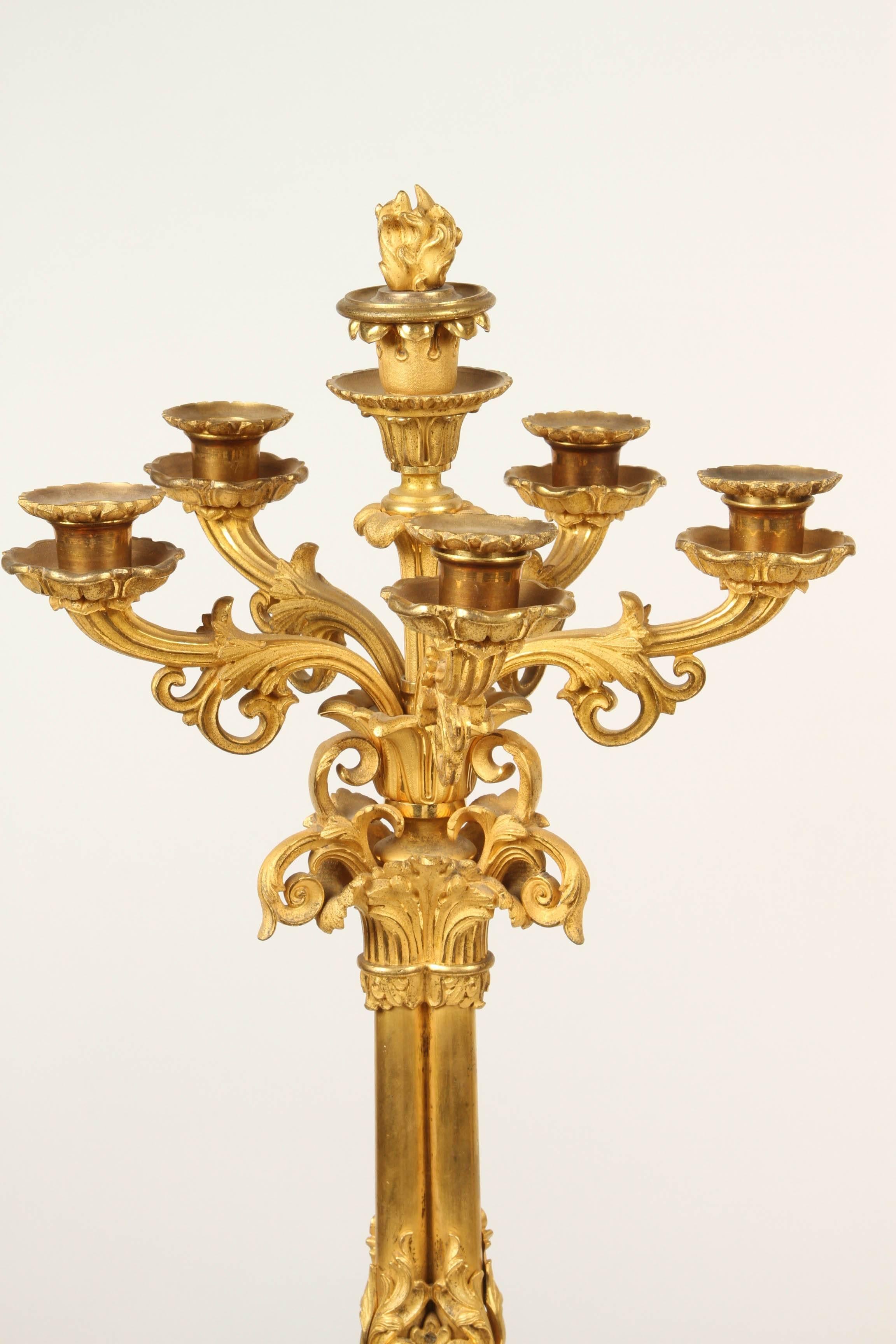 A fine pair of five branch, six candle ormolu candelabra. The candelabra rest on a triform base with foliate moulding, three feet. The tripartie stem holds the candelabra arms which are in the form of scrolling flower stems. Each candle sconce is