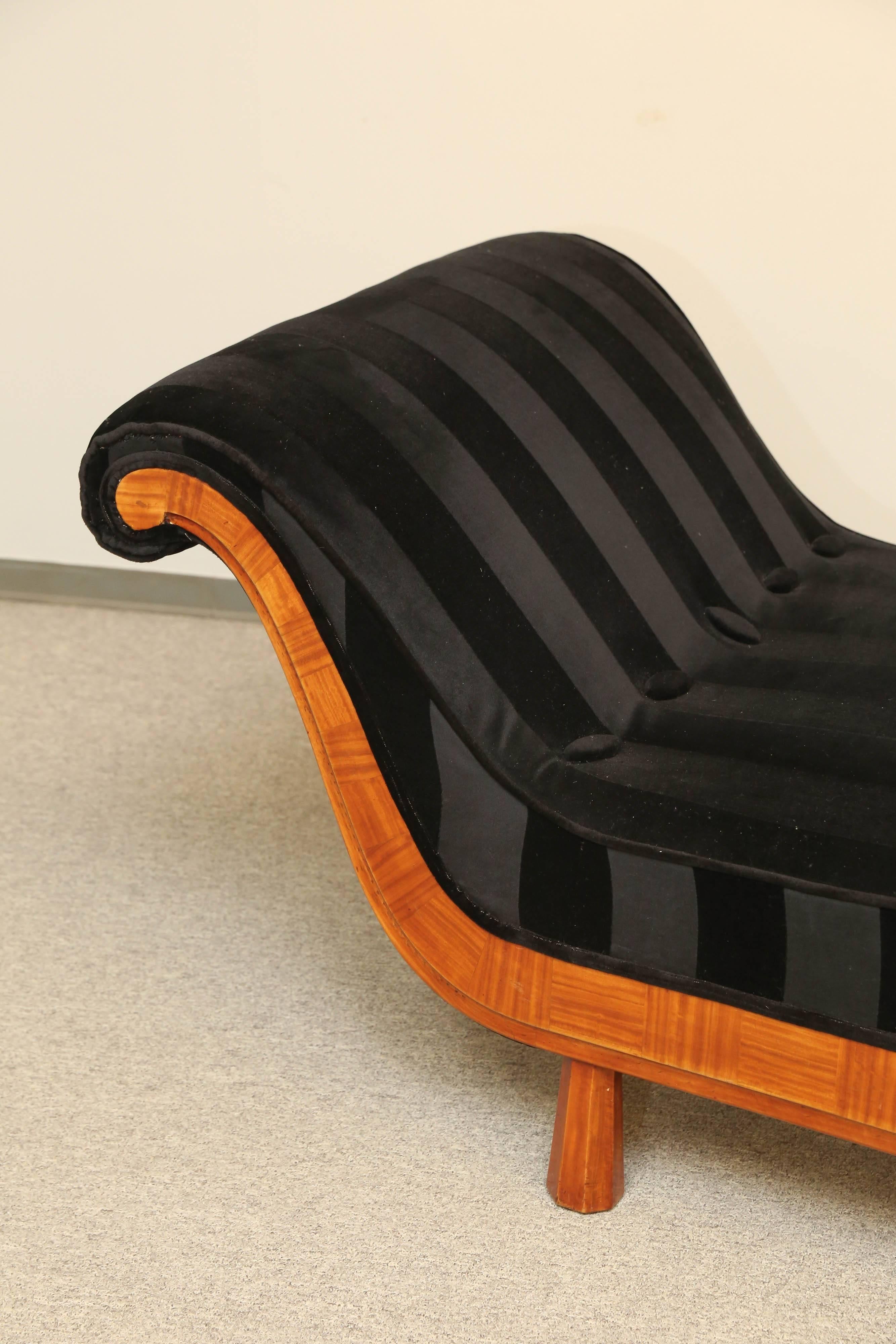 French Recamier with inlaid rosewood trim, resting on four shaped wood blocks. Covered in black on black stripes. Matching black bolster. Restored. 