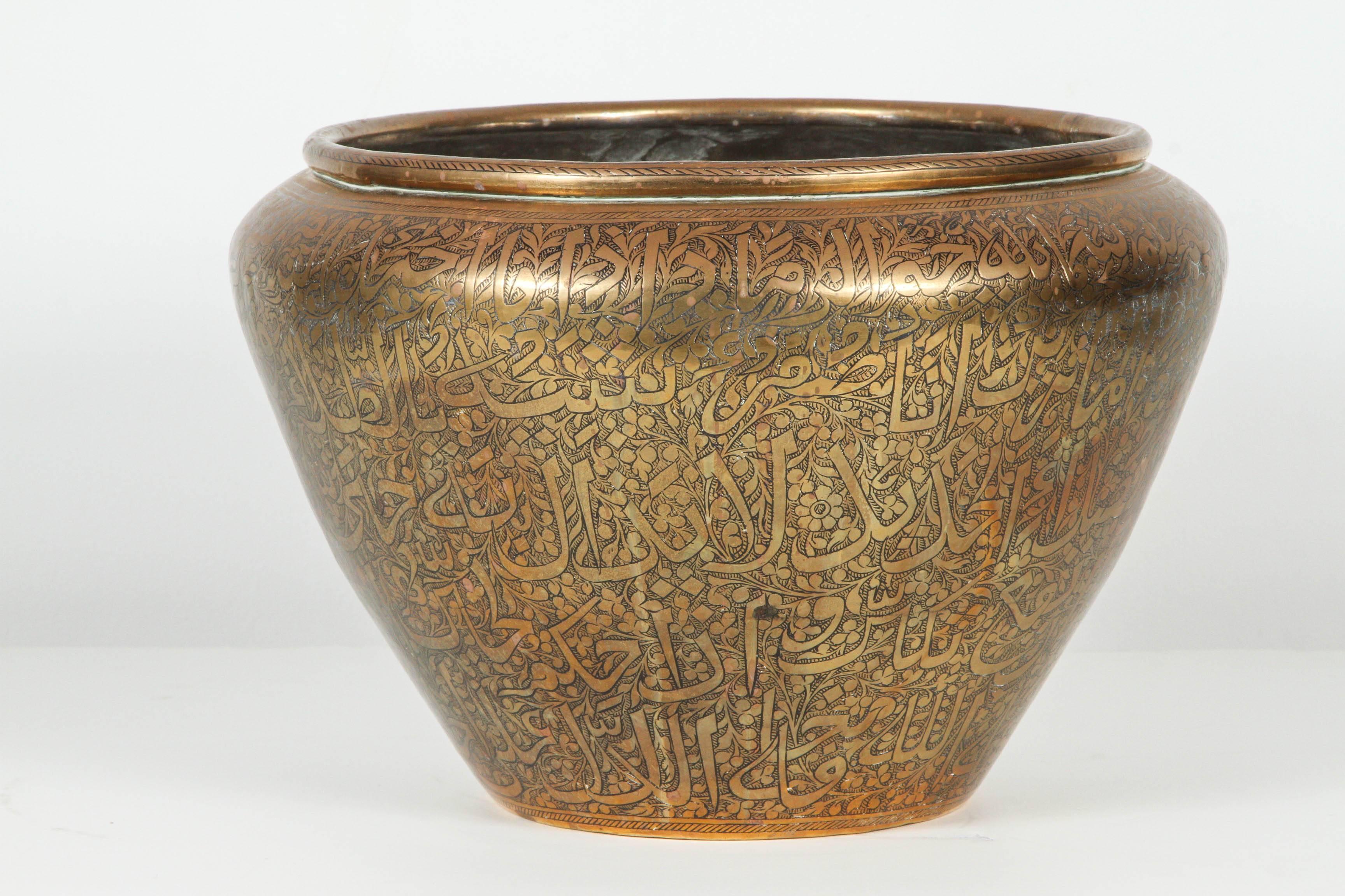 Very nice large brass pot with Arabic calligraphy writhing all over.
Middle Eastern hand-hetched and carved designs.