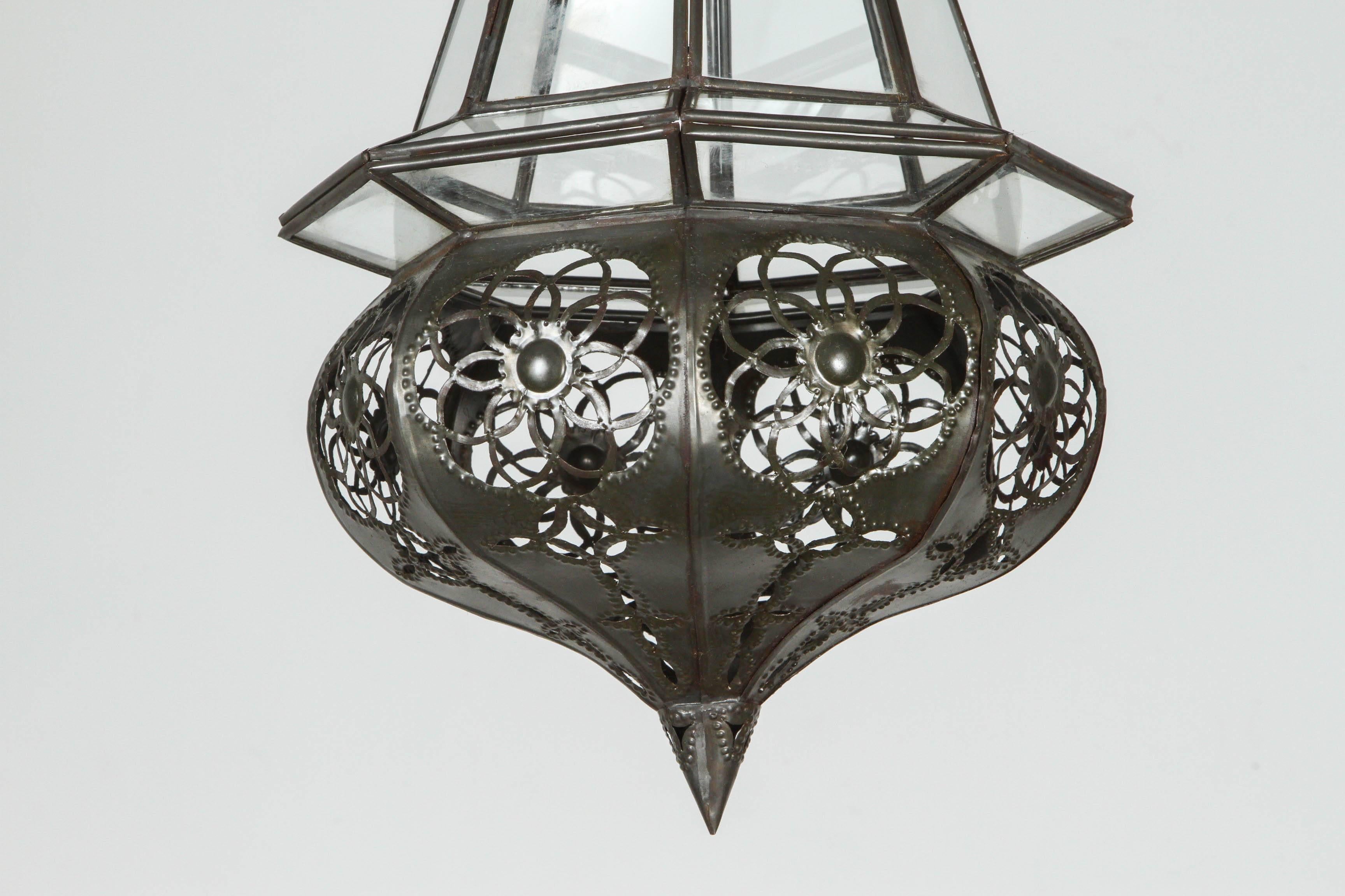 Handcrafted Moroccan clear glass metal pendant.
Finely hand-cut metal in Moorish floral and geometric designs.
Diamond shape light fixture in dark bronze metal color finish.
Rewired with one light bulb, comes with additional chain and canopy,