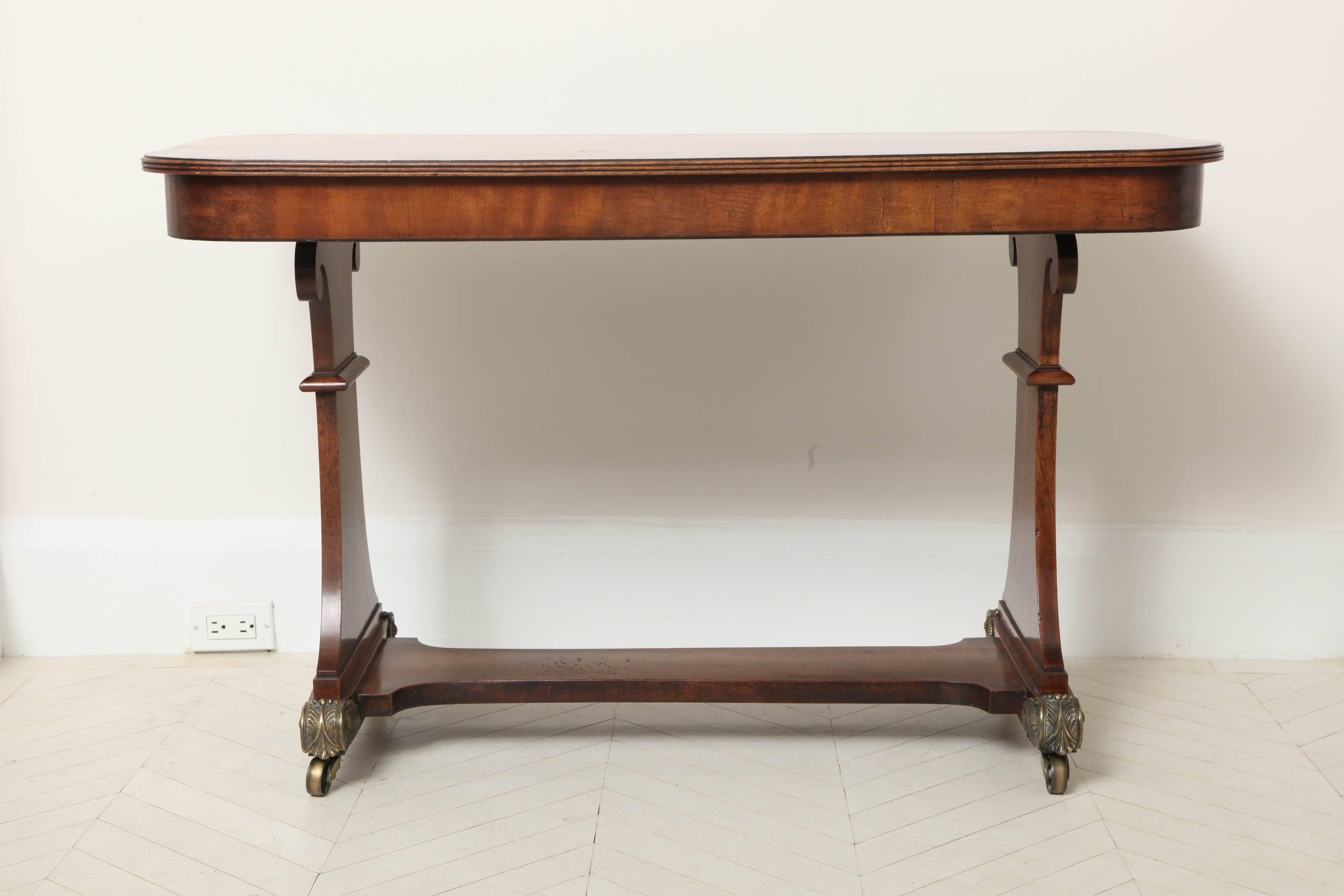 An English Regency faded mahogany center table with frieze drawer and lower stretcher on ormolu-mounted casters, circa 1820