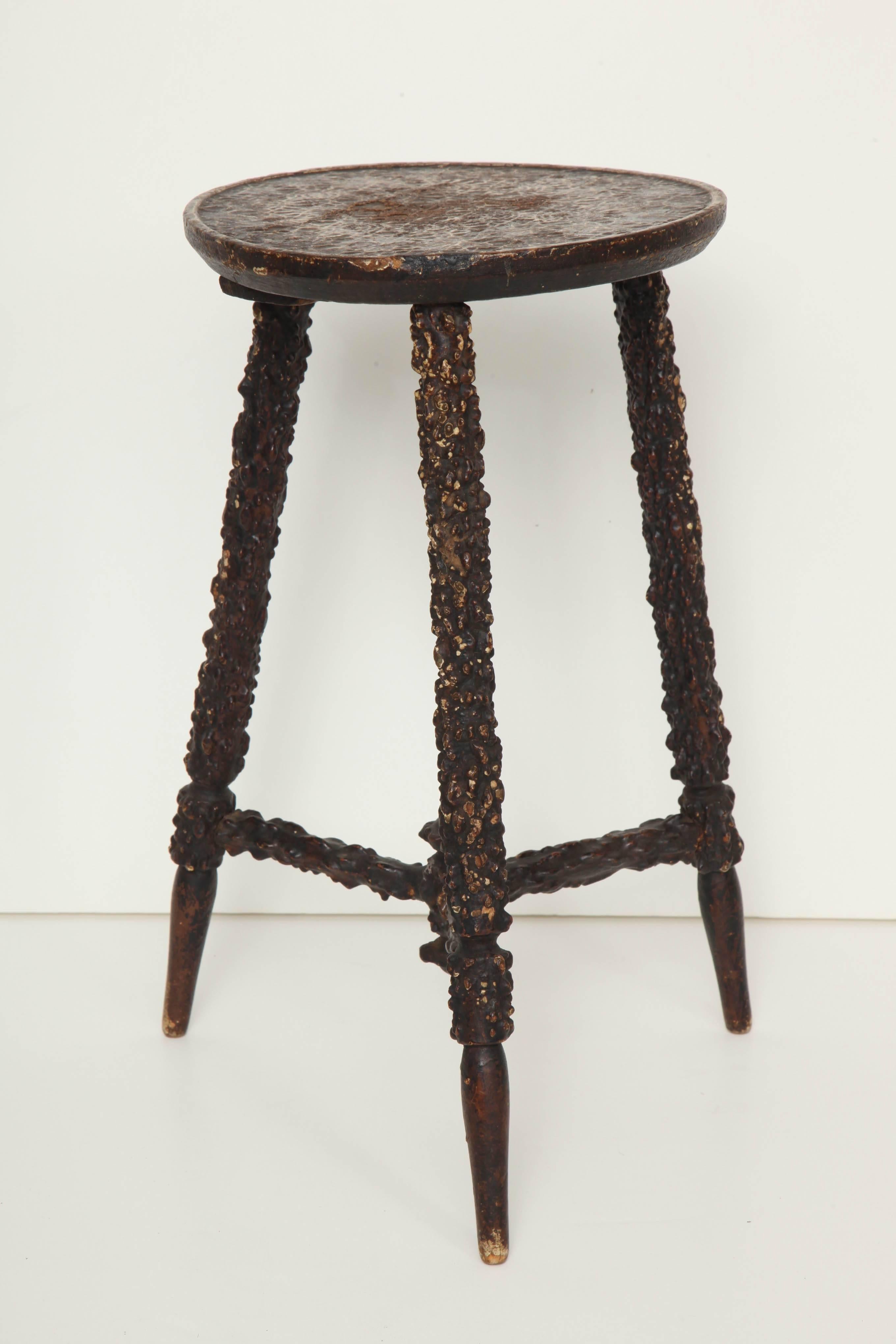 A late 19th century English rusticated three-legged stool with pressed papier mâché design on the seat and legs imitating naturally gnarled wood.