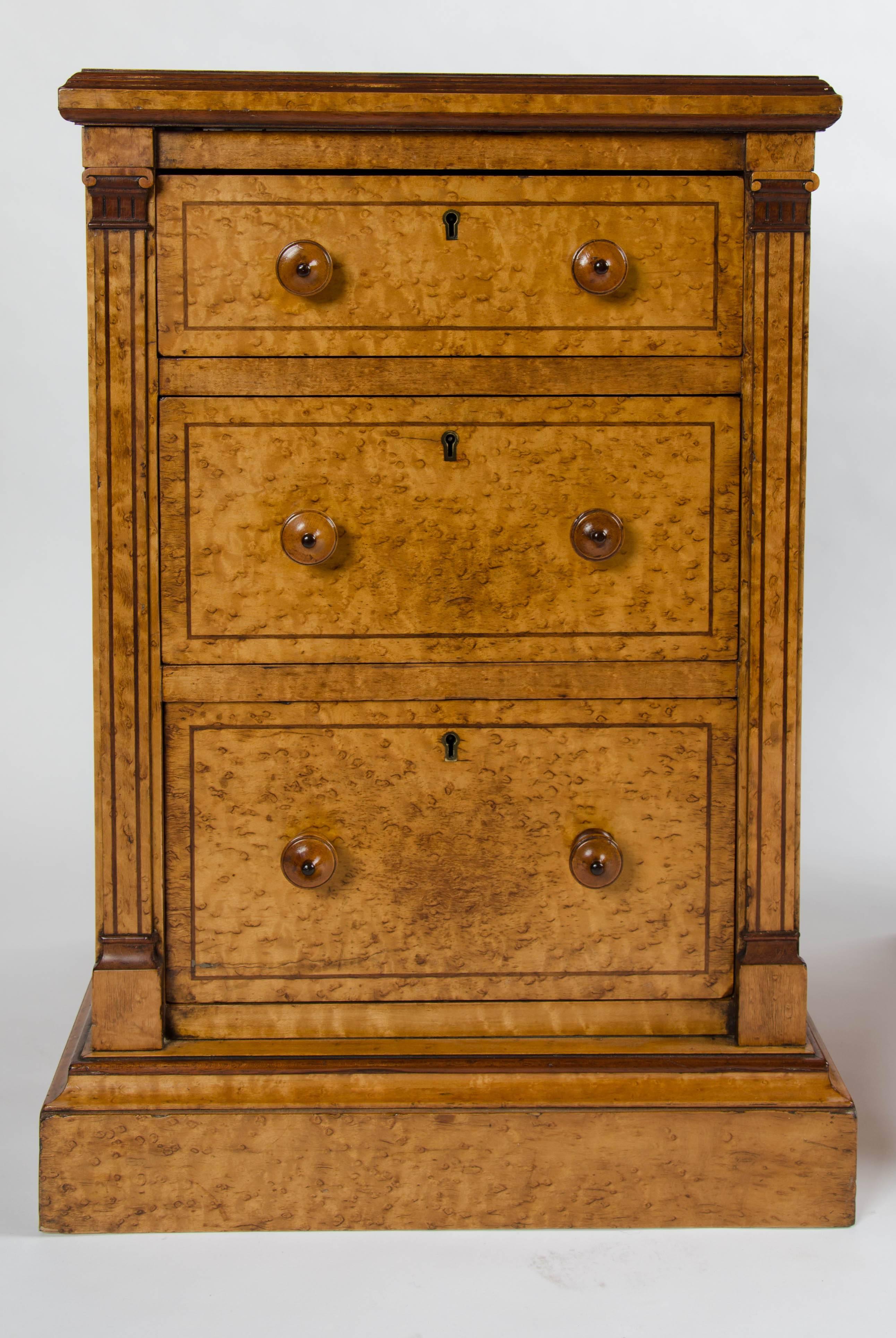 A very elegant pair of bedside chests of three graduating drawers in bird's-eye maple with turned wooden handles.
The mouldings around the tops and bases of purple heart as are the inlaid lines around the drawers, top and columns.