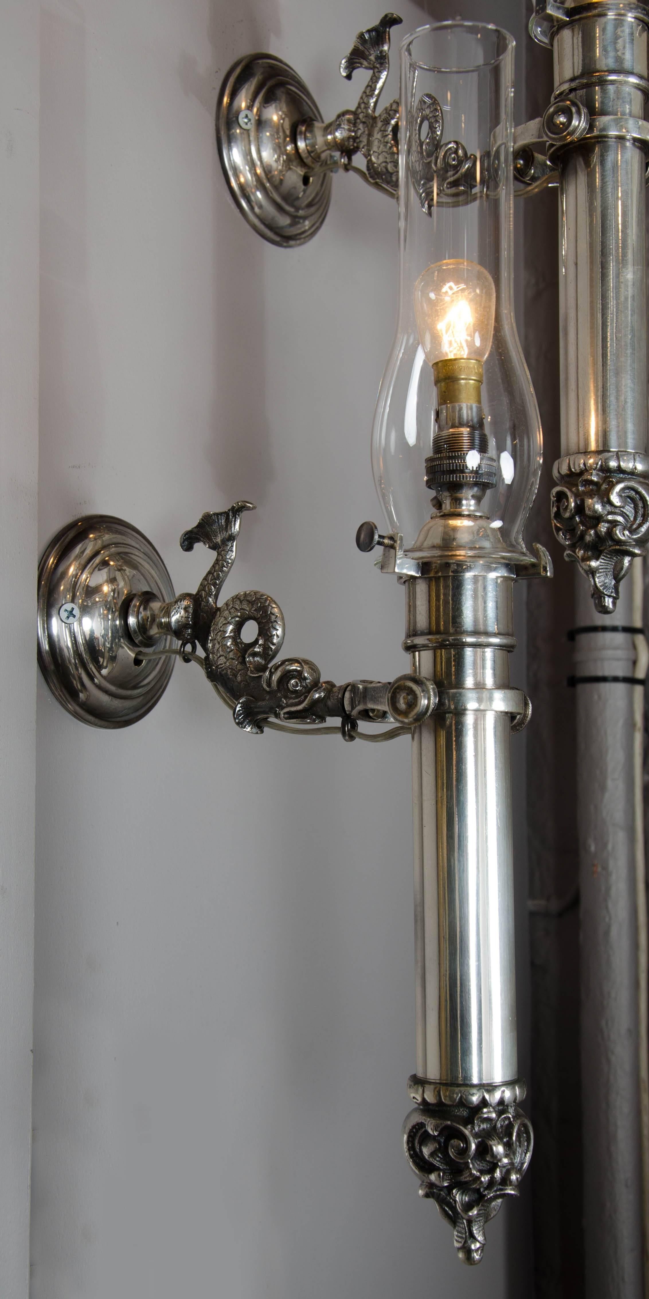 A stunning and rare pair of Victorian period silver plated gimballed ship's lights. Originally for candles with sprung loaded holders terminating in Rococo style decoration, now wired for electricity.
The supporting arms in the form of classical