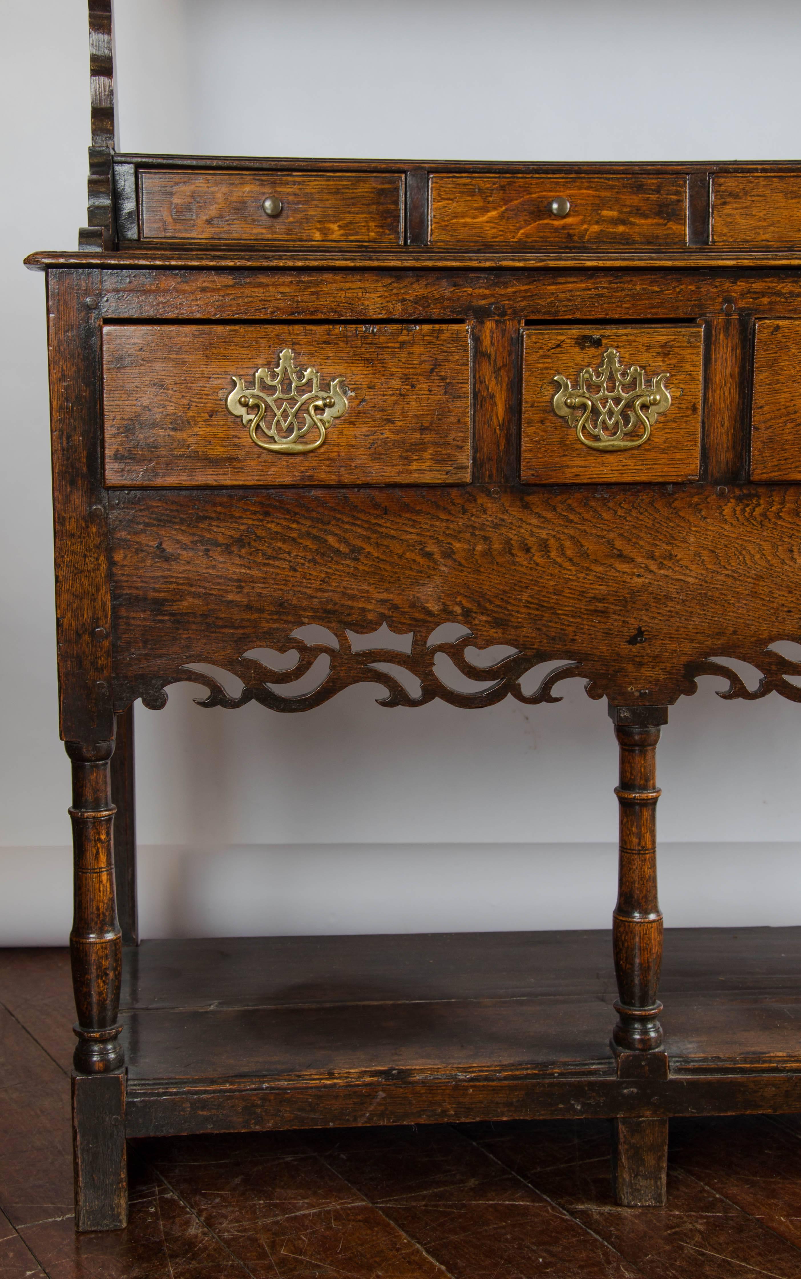 A charming late 18th century oak welsh dresser. The top with fine profiled supports, the base with five short drawers above five long drawers and pierced apron on turned legs.