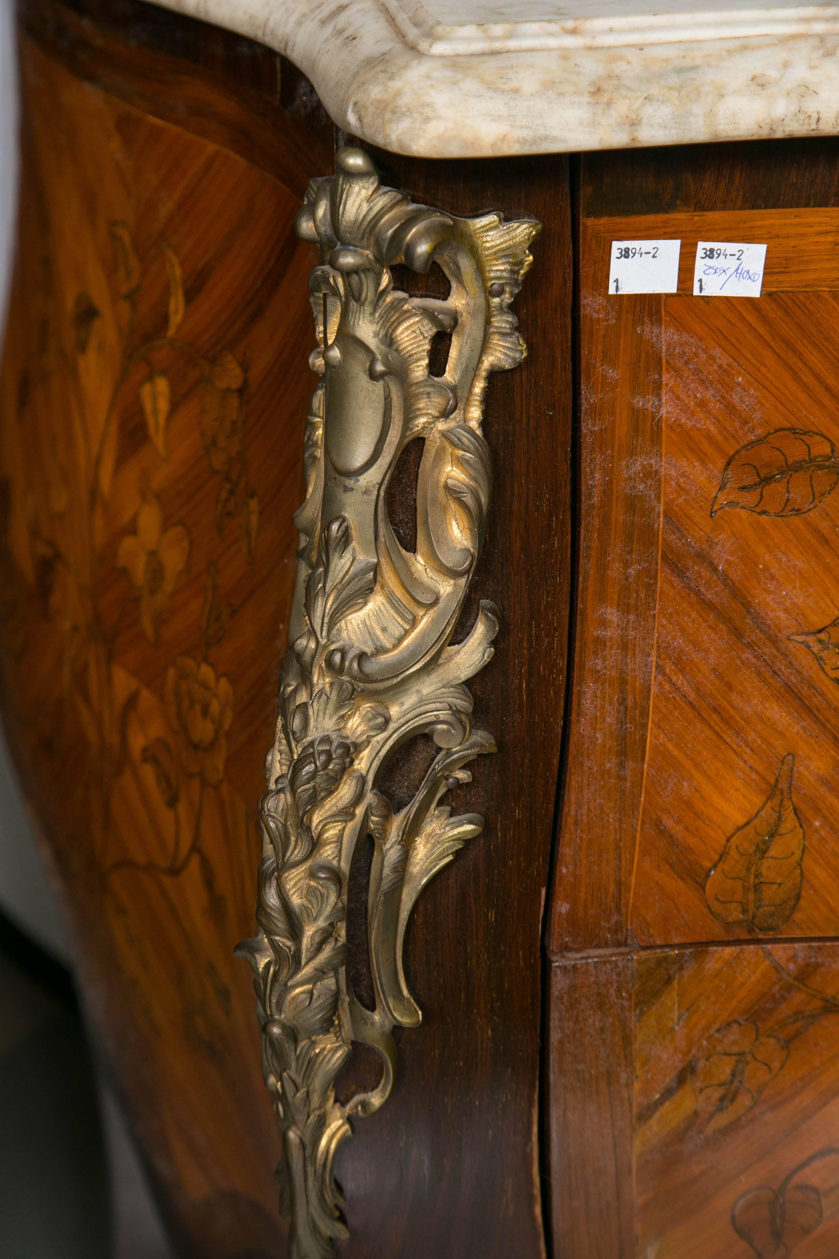 N. Metaism signed early 19th century bombe marble-top commode. The finely bronze mounted commode having a bombe case decorated with kings wood, satinwood and rosewood veneers with an all-over large flowing basket of floral and leaf with vine design.