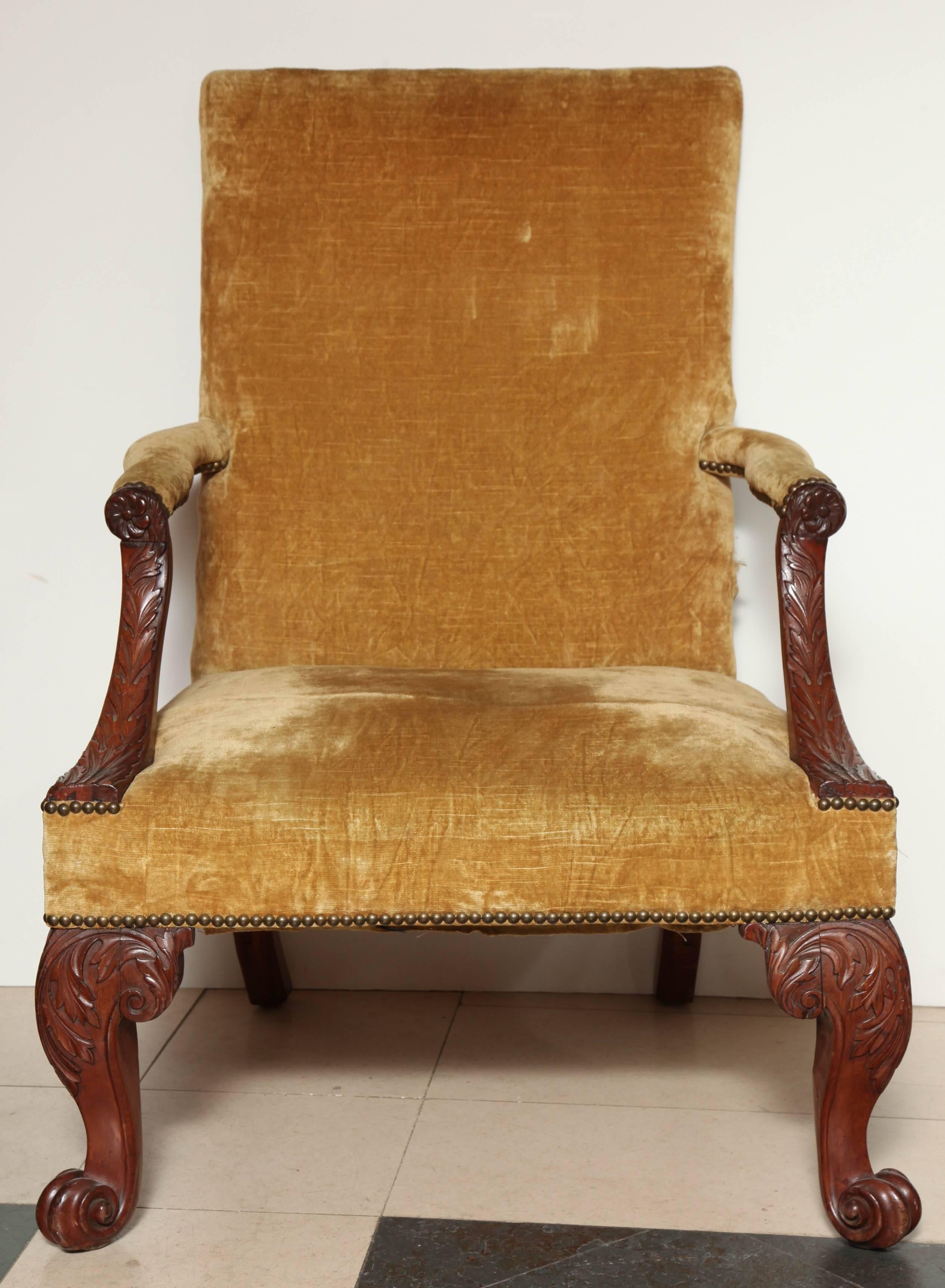 An English George III carved mahogany Gainsborough chair with leaf carved arm supports and front cabriole legs ending in scroll feet.
Re-framed. 