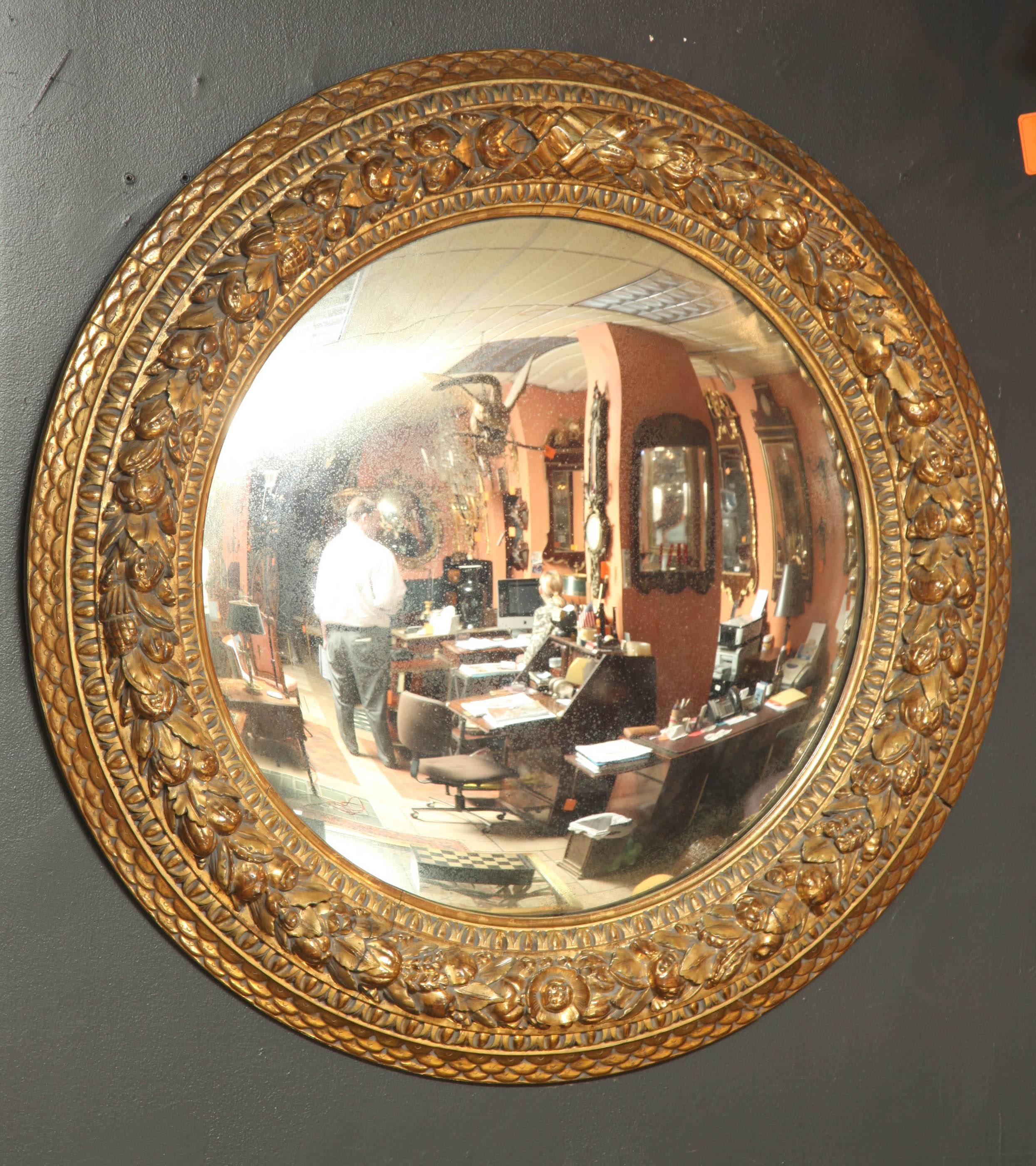 Very large Napoleon III giltwood convex mirror with richly carved fruit and foliate surround.