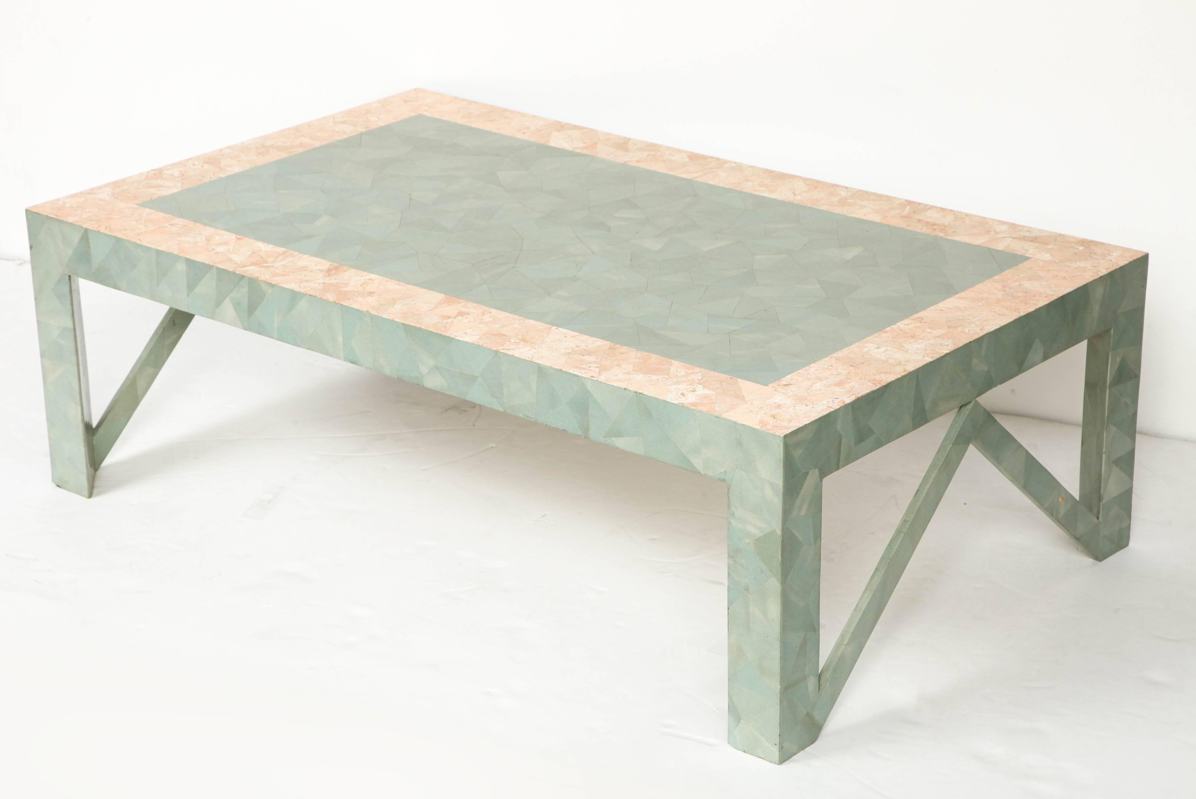 This large rectangular coffee table has on its surface a border of pastel rose-orange which contrasts with the pastel green tessellated pattern.
It reminds one of Karl Springer work. 
It is in perfect condition and has been recently refinished