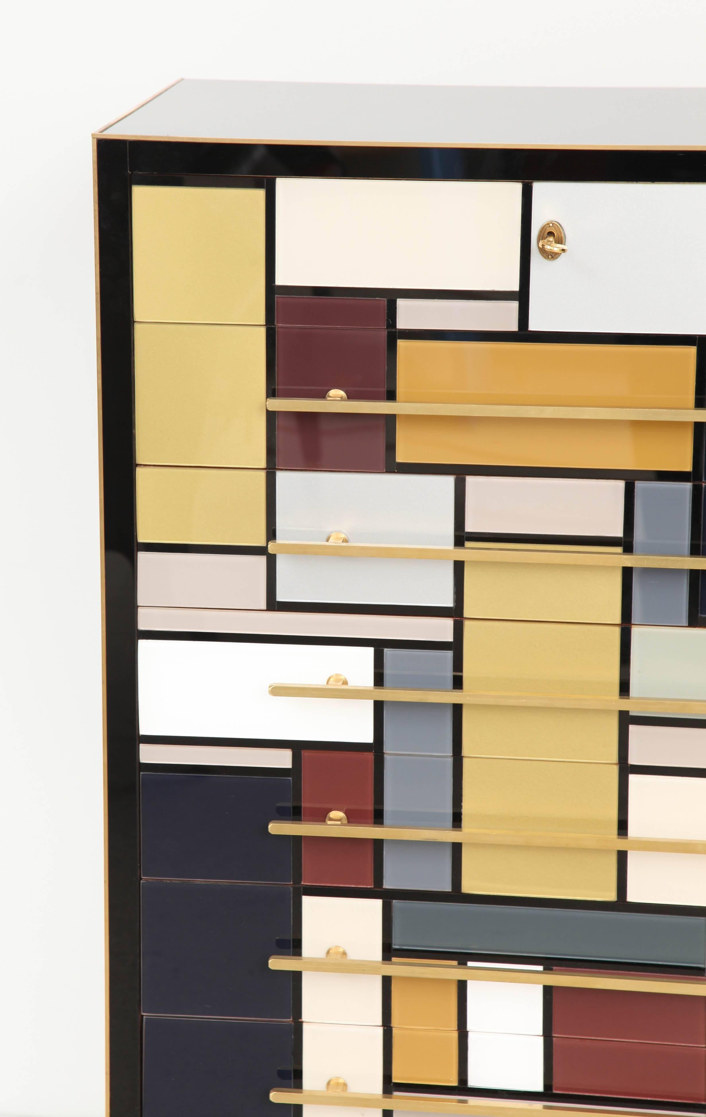 This Italian mid-century tall chest of drawers or dresser is absolutely exquisite. Made of wood and covered in individually cut and pieced together high-gloss grey, white, yellow, burgundy and black colored venetian Opaline glass with beautiful