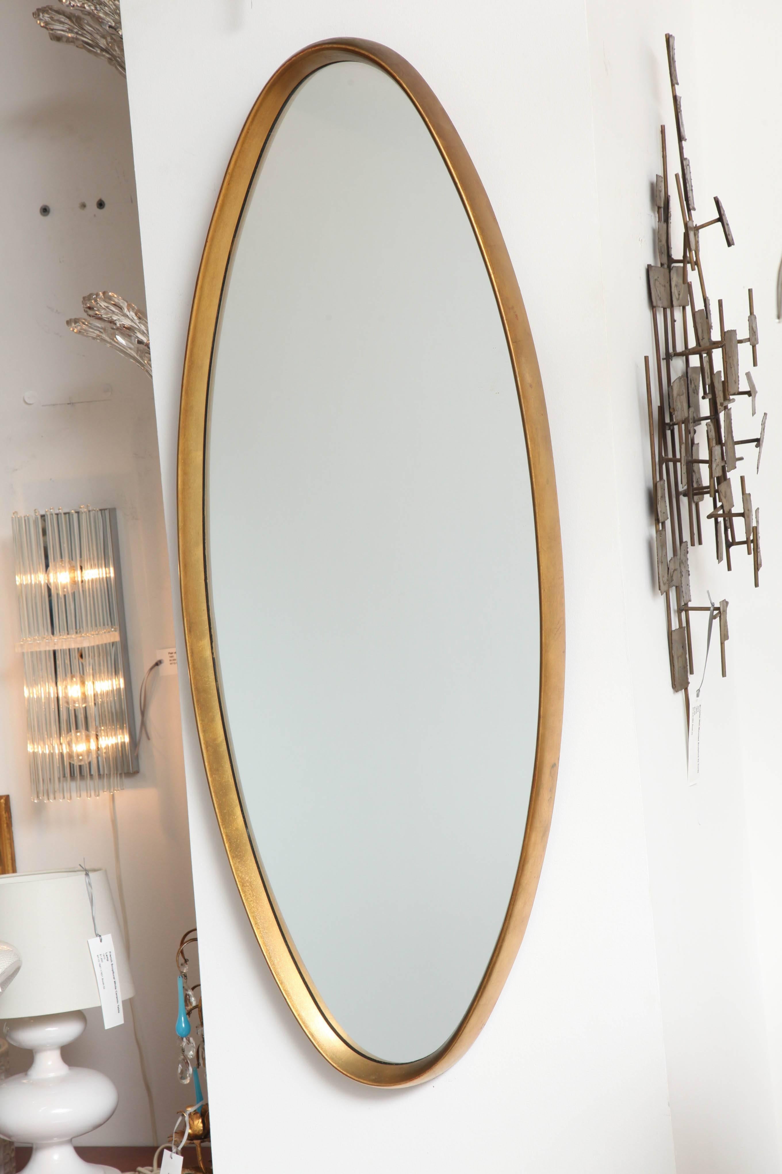 An elegant ellipse-shaped wall mirror with matte gold-finished wood frame. Possibly made by La Barge, USA, circa 1960-1970.