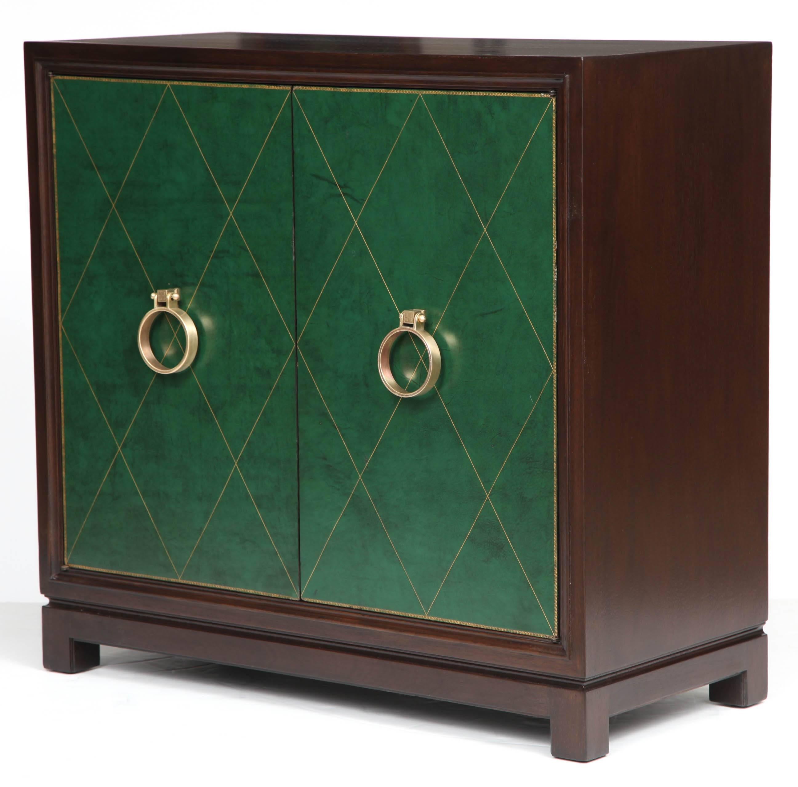 Classic Midcentury Walnut cabinet with tooled diamond patterned green leather door panels and satin brass door knocker pulls. Cabinet features two adjustable interior shelves. Perfectly sized for an entry way console, buffet cabinet or dry bar.