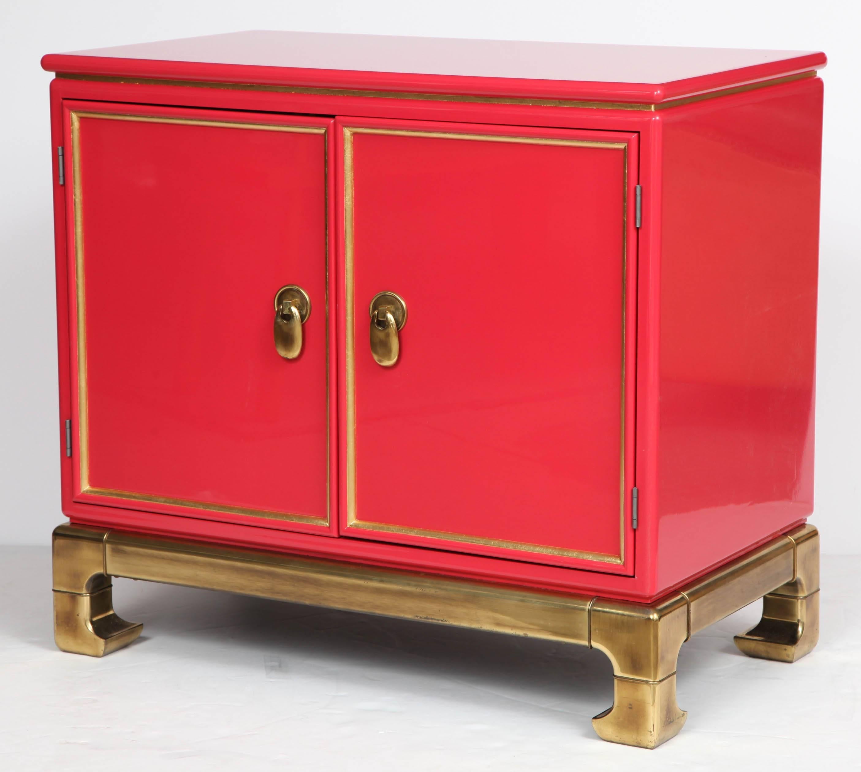 Mid-Century chinoiserie influenced cabinet in a poppy lacquer with gold leaf details resting on a heavy brass base. Perfectly sized for an entry area or dry bar.